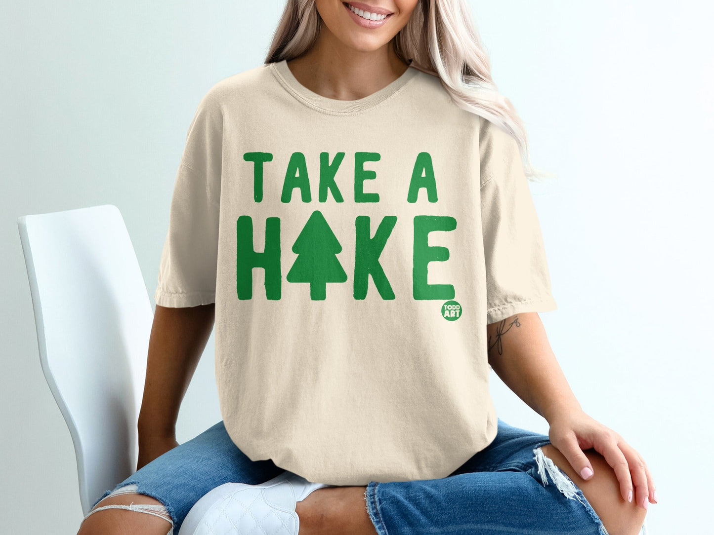 Cream t-shirt with green "TAKE A HIKE" text and a tree graphic.