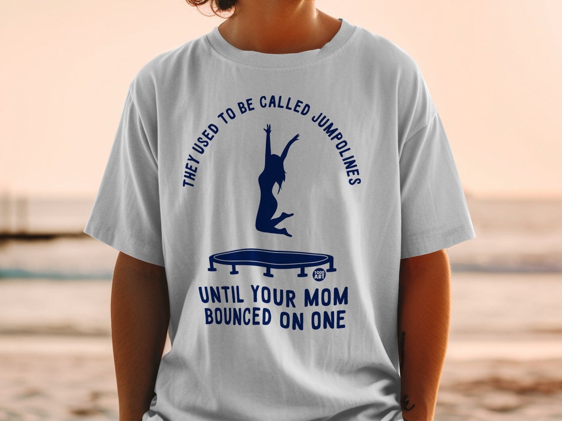 T-shirt with trampoline graphic and text "They used to be called Jumpolines until your mom bounced on one".