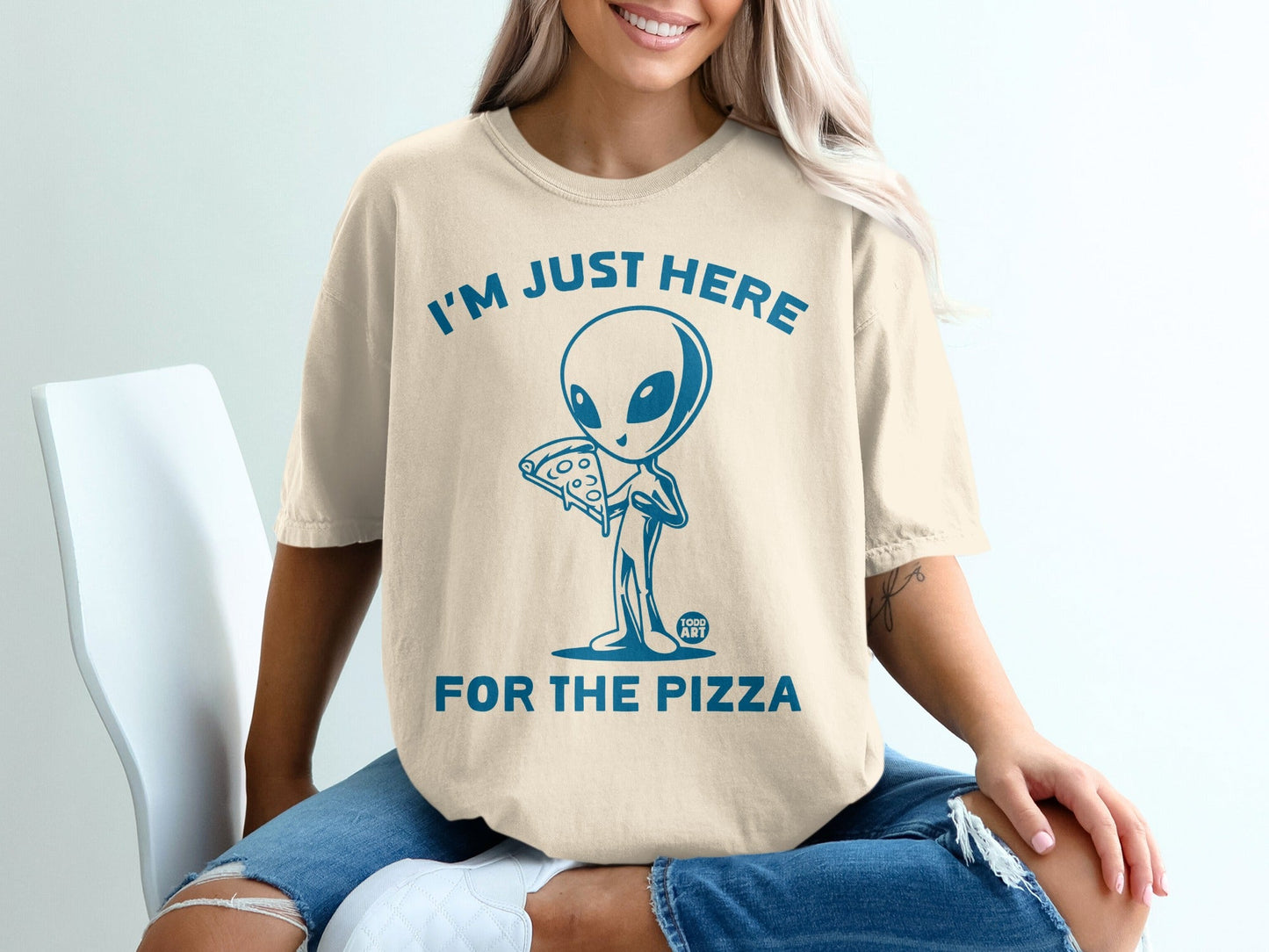 Beige t-shirt with "I'M JUST HERE FOR THE PIZZA" and alien graphic.