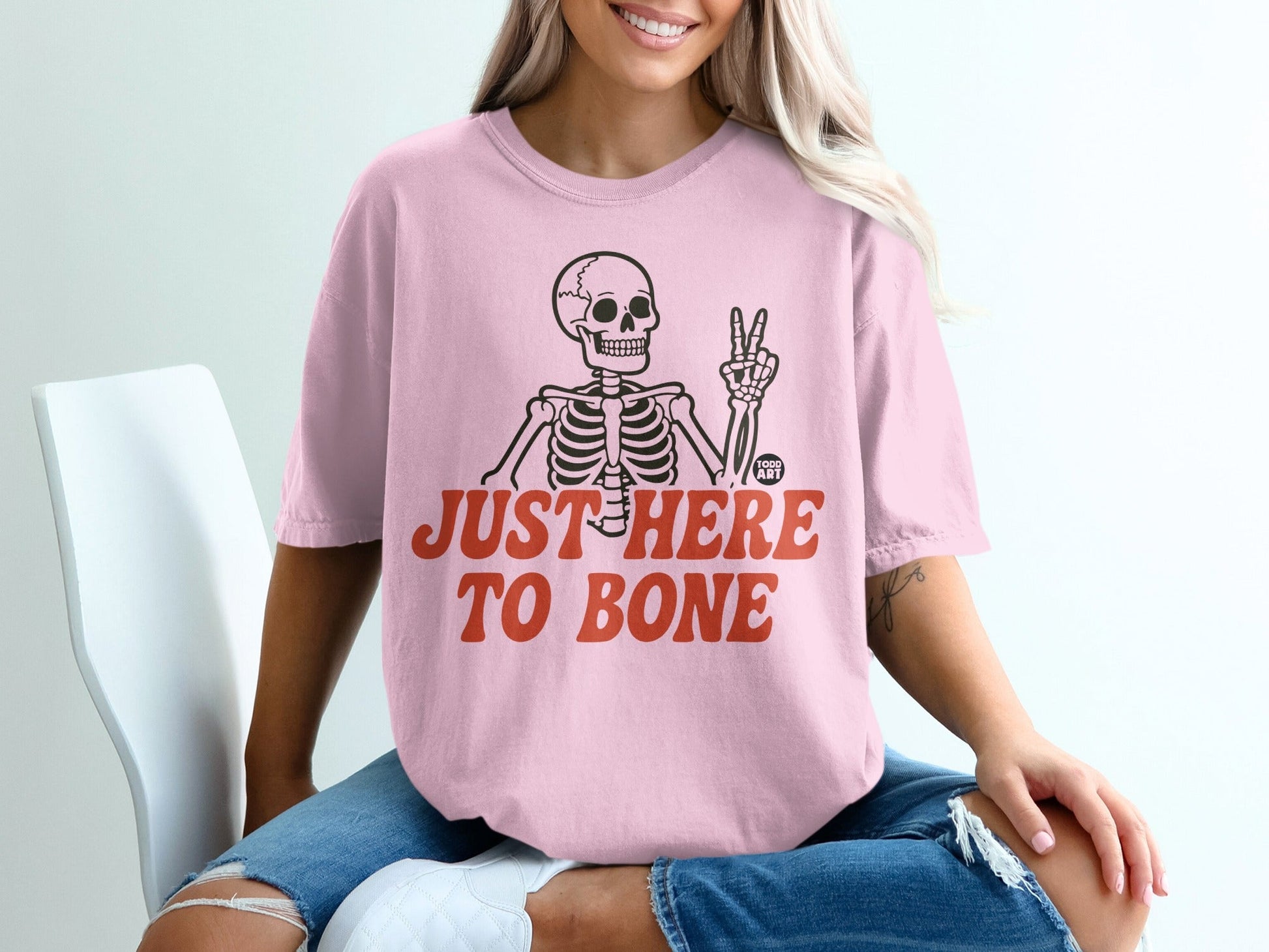 Pink t-shirt with skeleton and "Just Here To Bone" text.