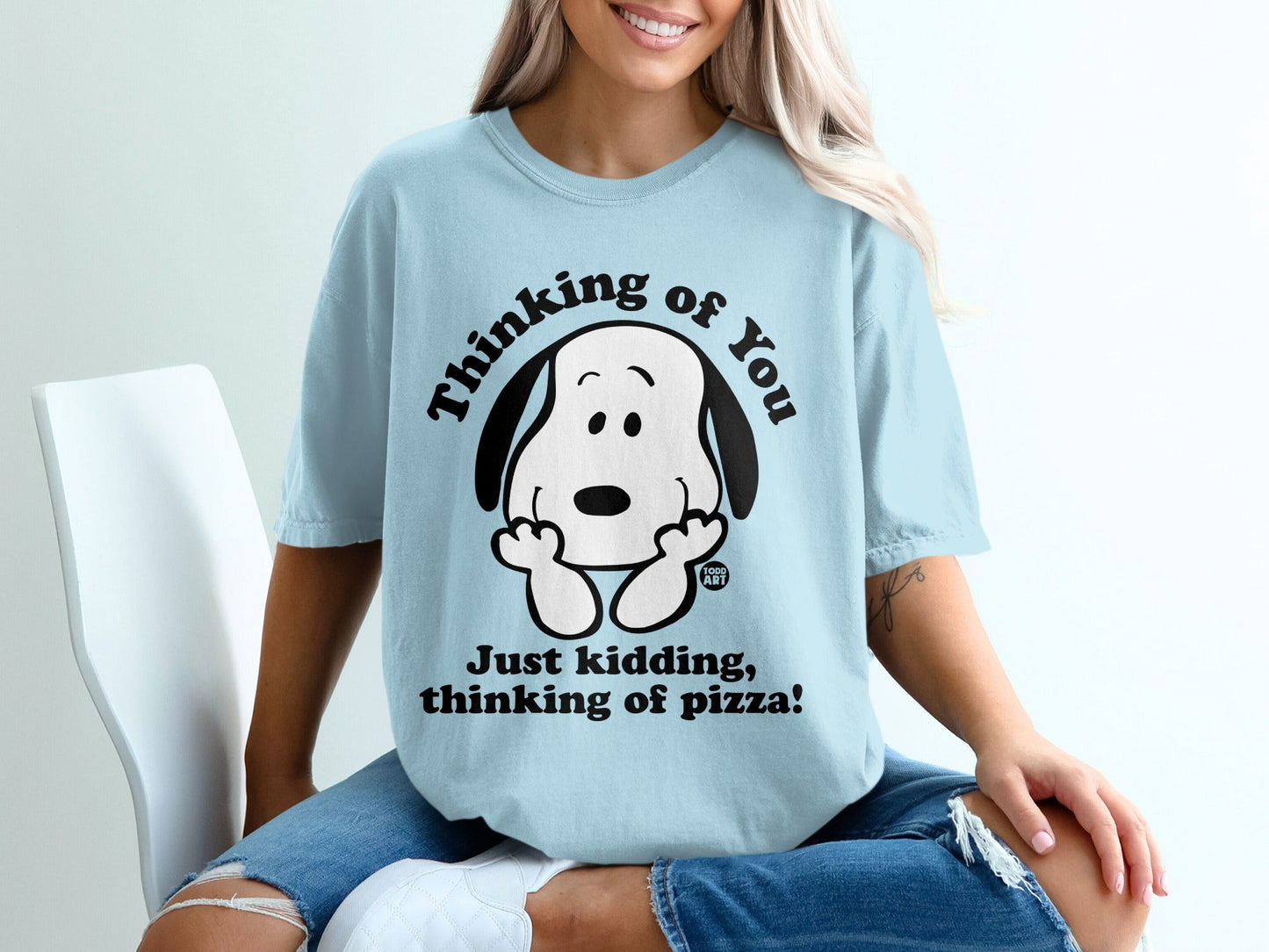 Light blue t-shirt with Snoopy saying "Thinking of you! Just kidding, thinking of pizza!".