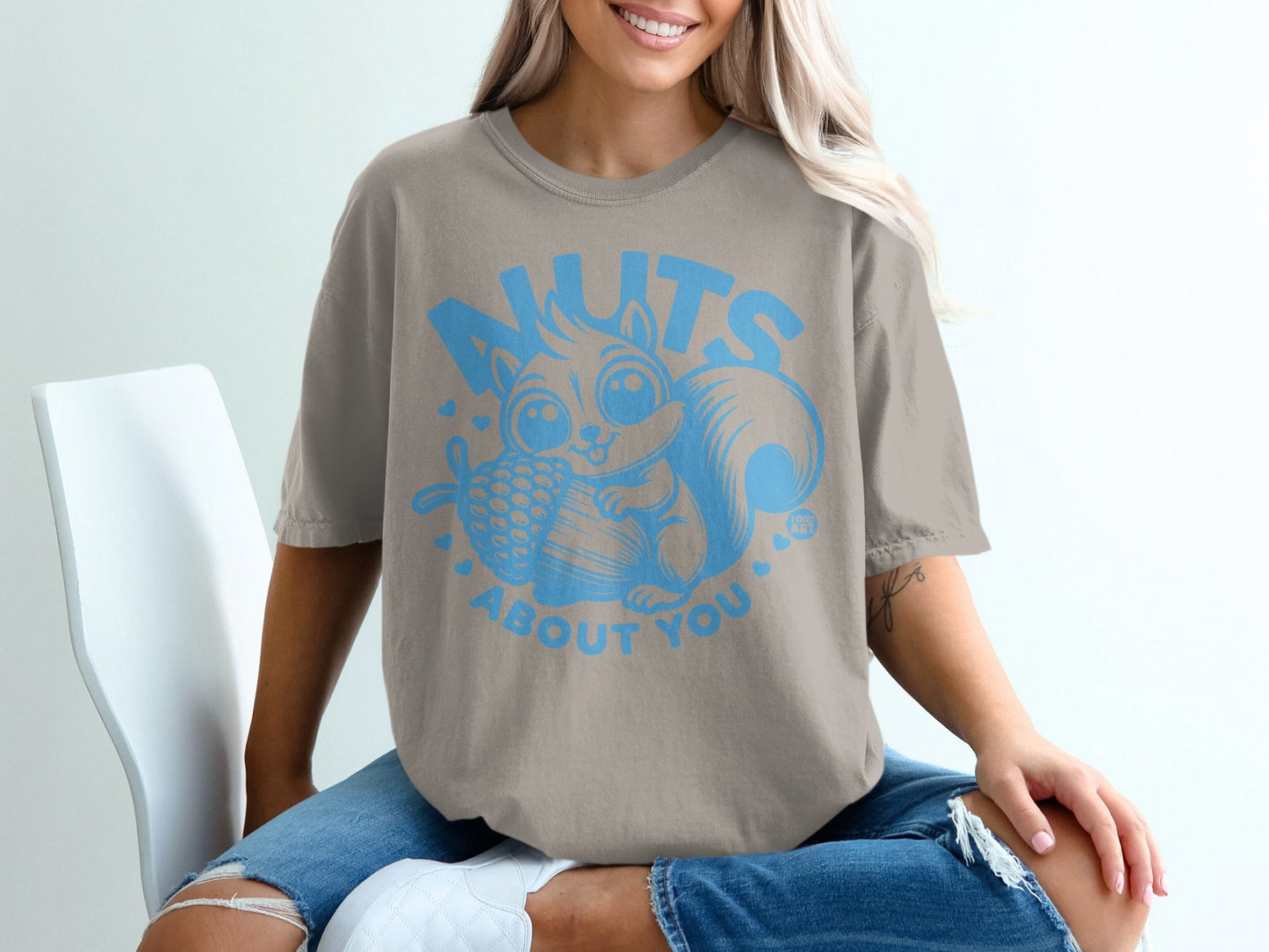 Graphic t-shirt with a cartoon squirrel holding a pinecone and the text "NUTS ABOUT YOU".