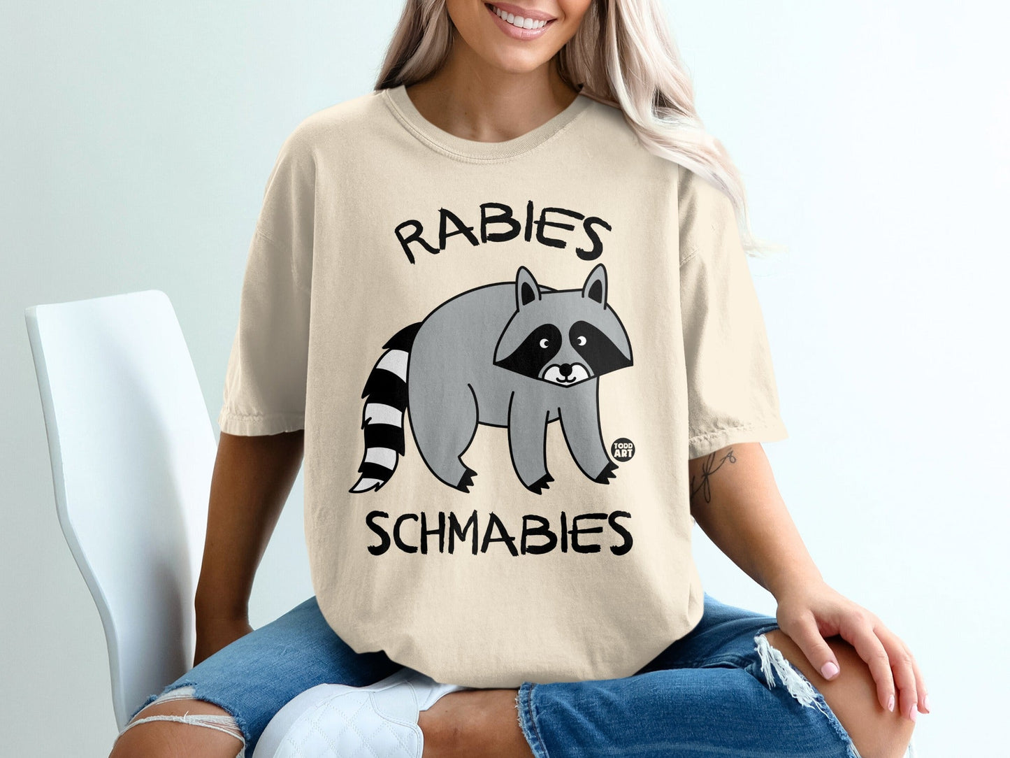 T-shirt with raccoon graphic and text "RABIES SCHMABIES".