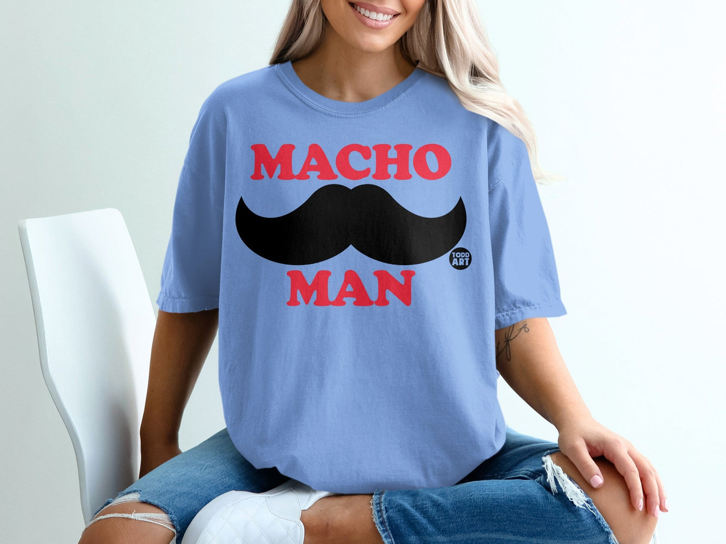 Light blue t-shirt with "MACHO MAN" and a large black mustache graphic.