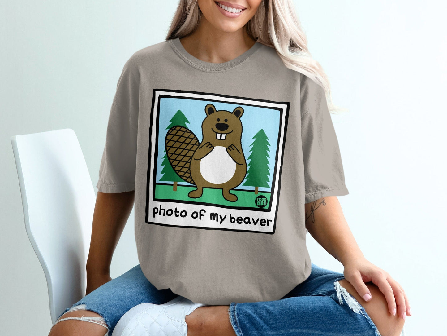 Cartoon beaver standing between two pine trees with "photo of my beaver" text.