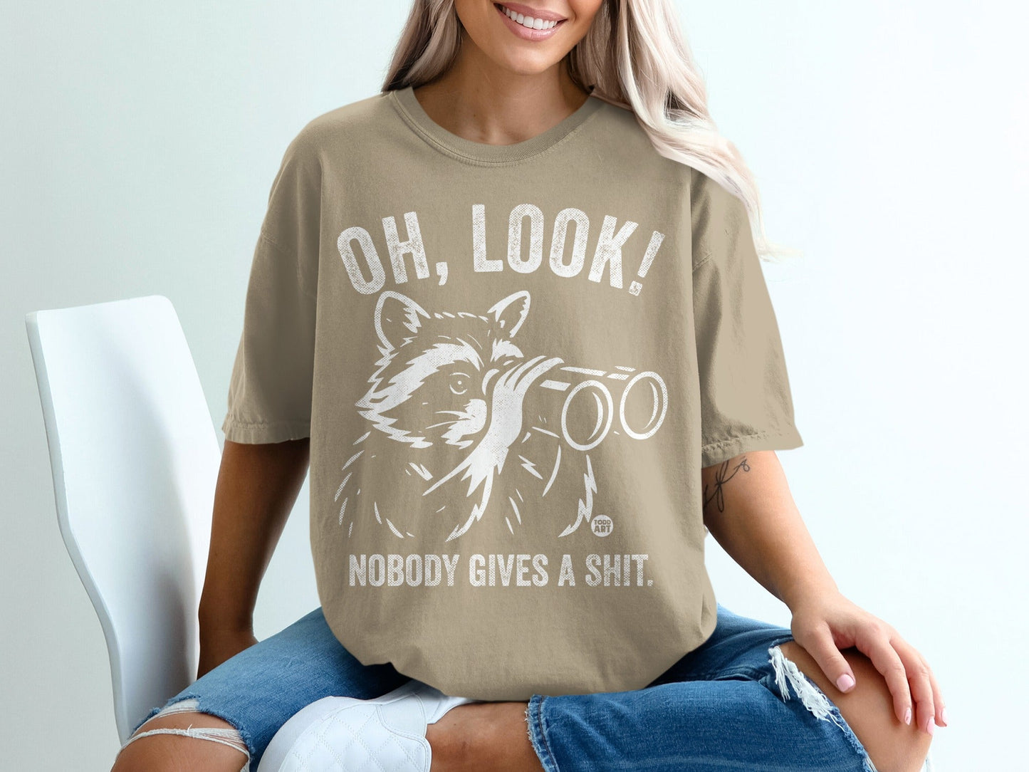 T-shirt with raccoon looking through binoculars, text reads "Oh, look! Nobody gives a shit."