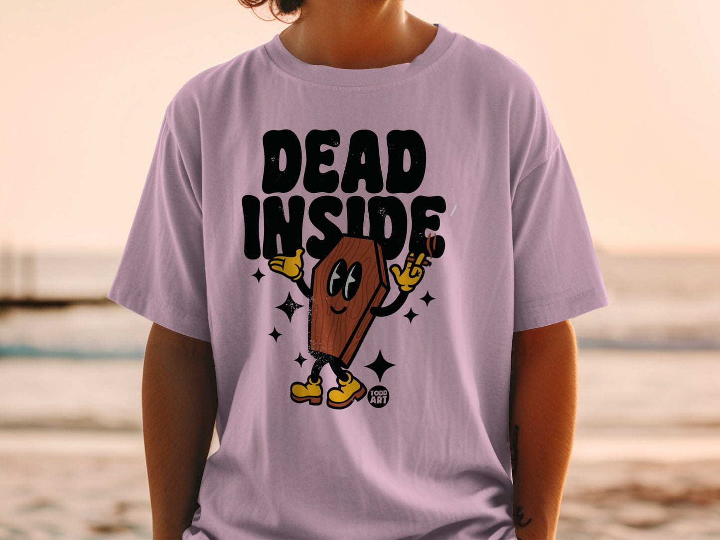 Pink t-shirt with "DEAD INSIDE" text and a cartoon coffin character holding a cigarette.
