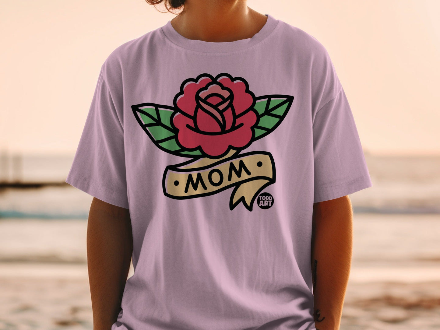 Pink t-shirt with a vintage-style rose and "MOM" banner tattoo design.