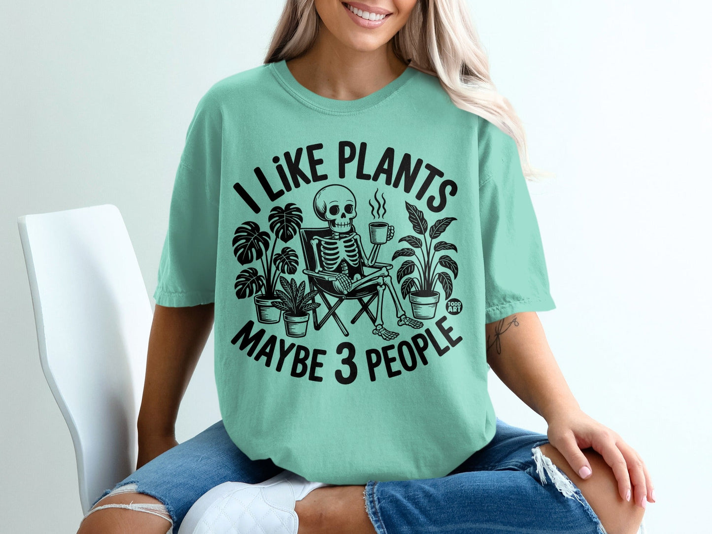 Skeleton sitting in a chair with plants and coffee, text "I like plants maybe 3 people".