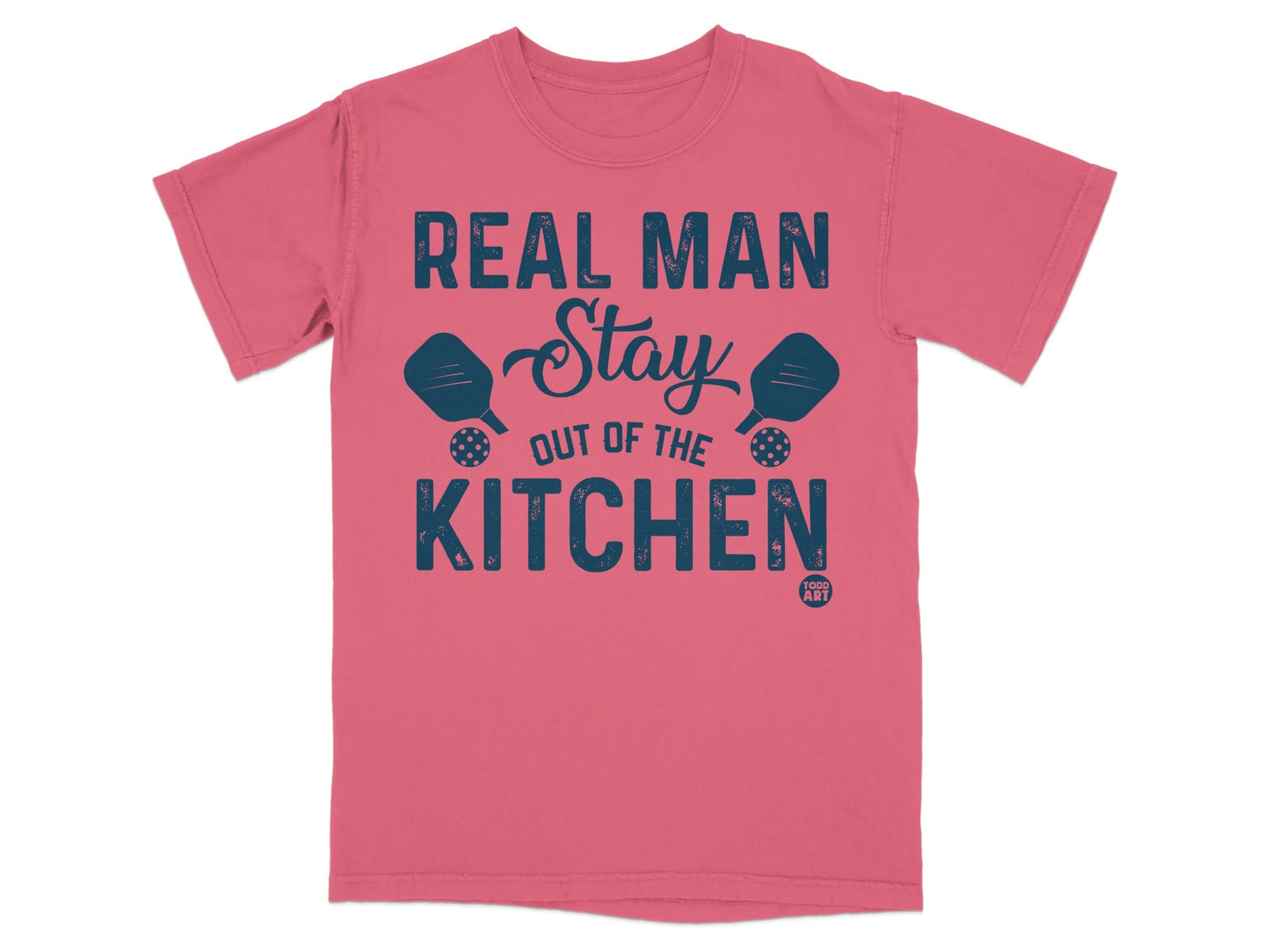 Coral t-shirt with "Real Man Stay Out of the Kitchen" text and pickleball paddles.