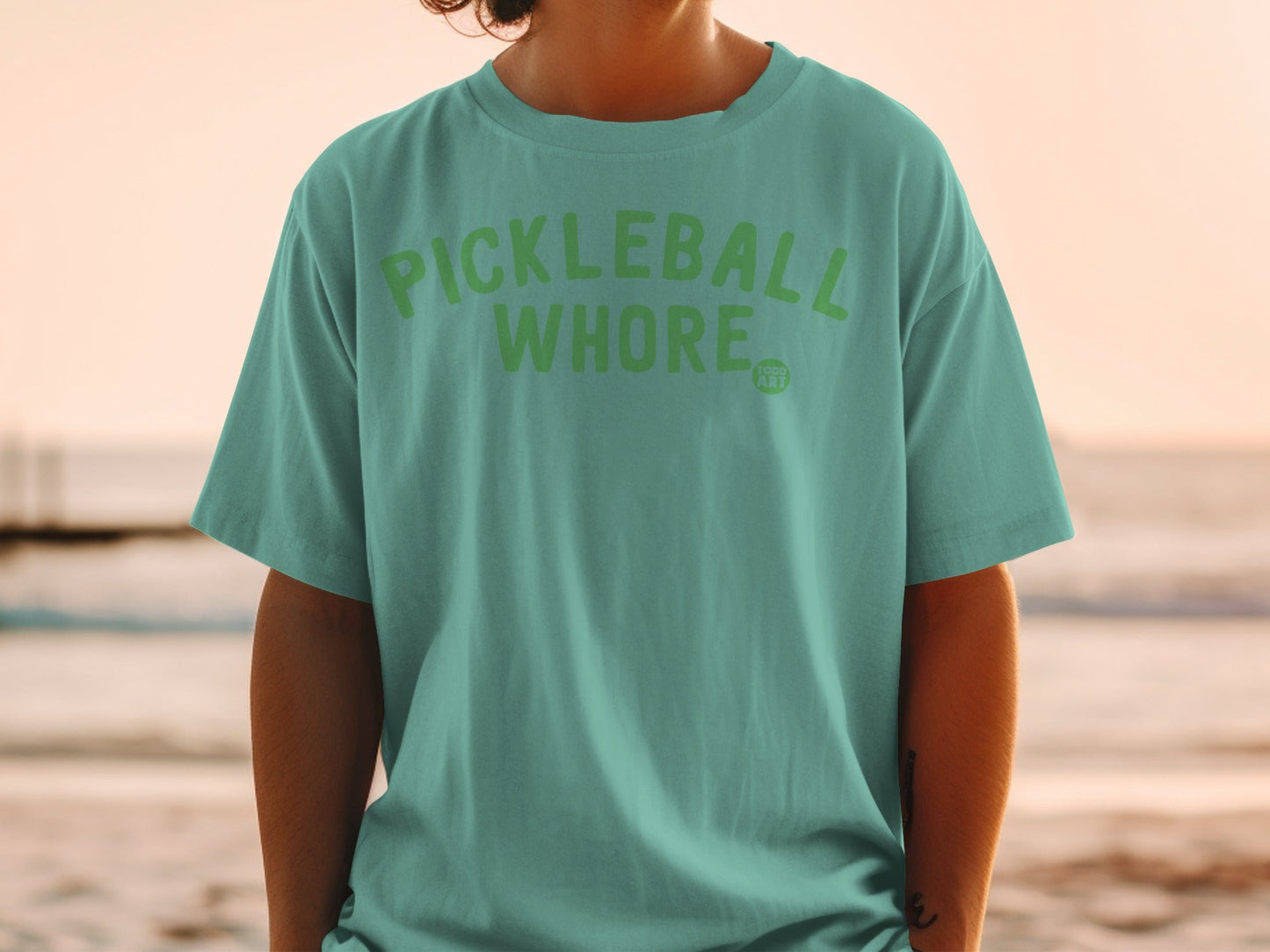 Teal t-shirt with "PICKLEBALL WHORE" in green lettering.