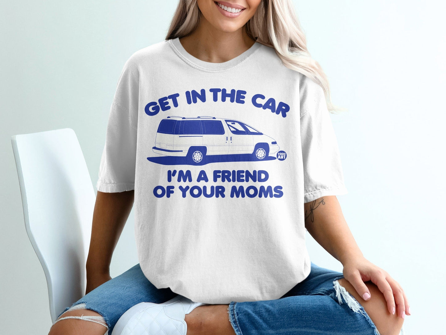 White t-shirt with blue text "GET IN THE CAR I'M A FRIEND OF YOUR MOMS" and minivan graphic.