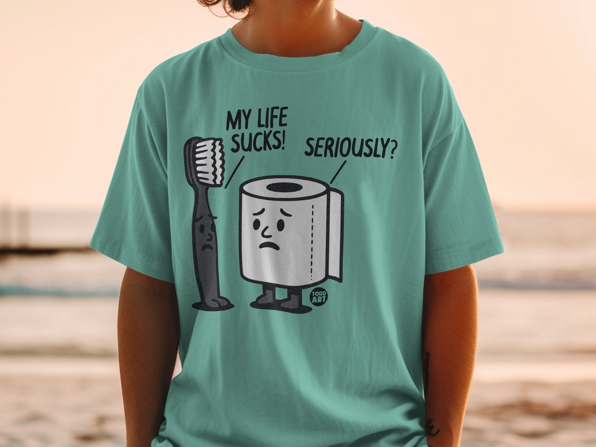 T-shirt graphic: Sad toothbrush and toilet paper with "MY LIFE SUCKS! SERIOUSLY?"
