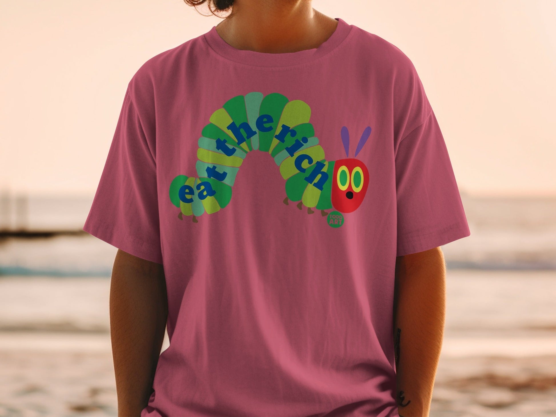 T-shirt with a green caterpillar eating the words "the rich".
