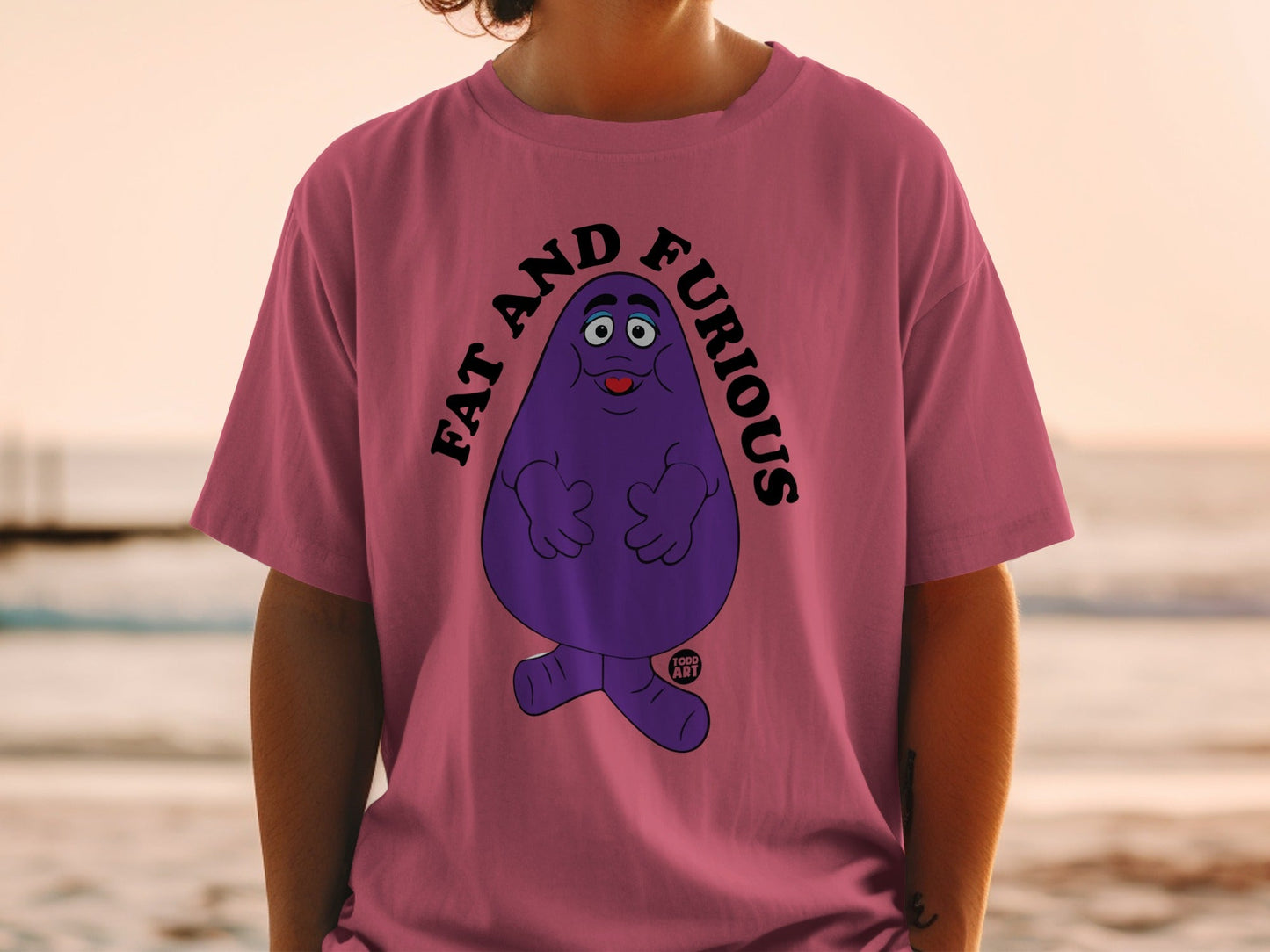 Purple Grimace character on a pink t-shirt with "FAT AND FURIOUS" text.