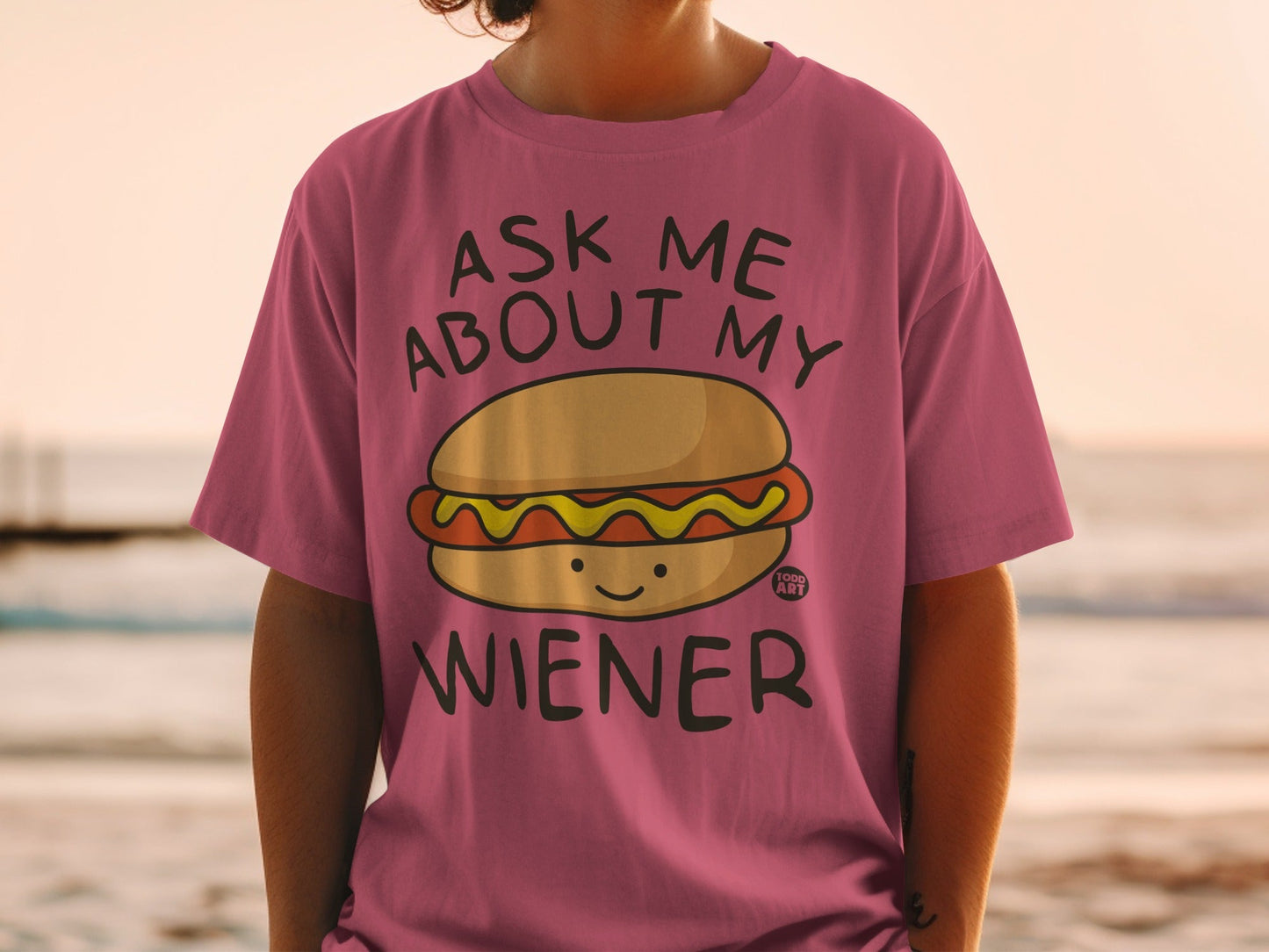 Pink t-shirt with cartoon hot dog and "Ask Me About My Wiener" text.