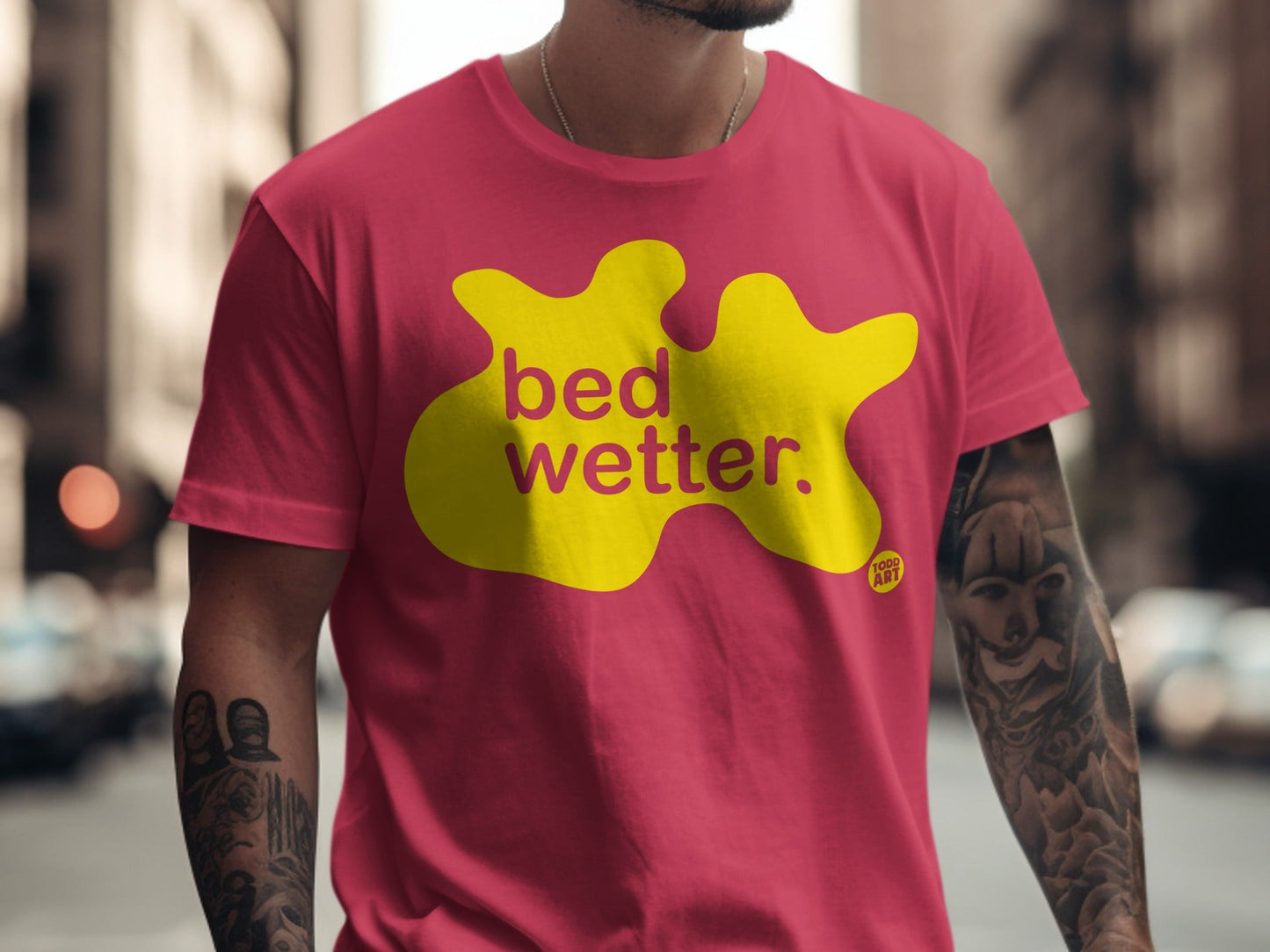 Red t-shirt with yellow "bed wetter" graphic and "TOPS ART" logo.
