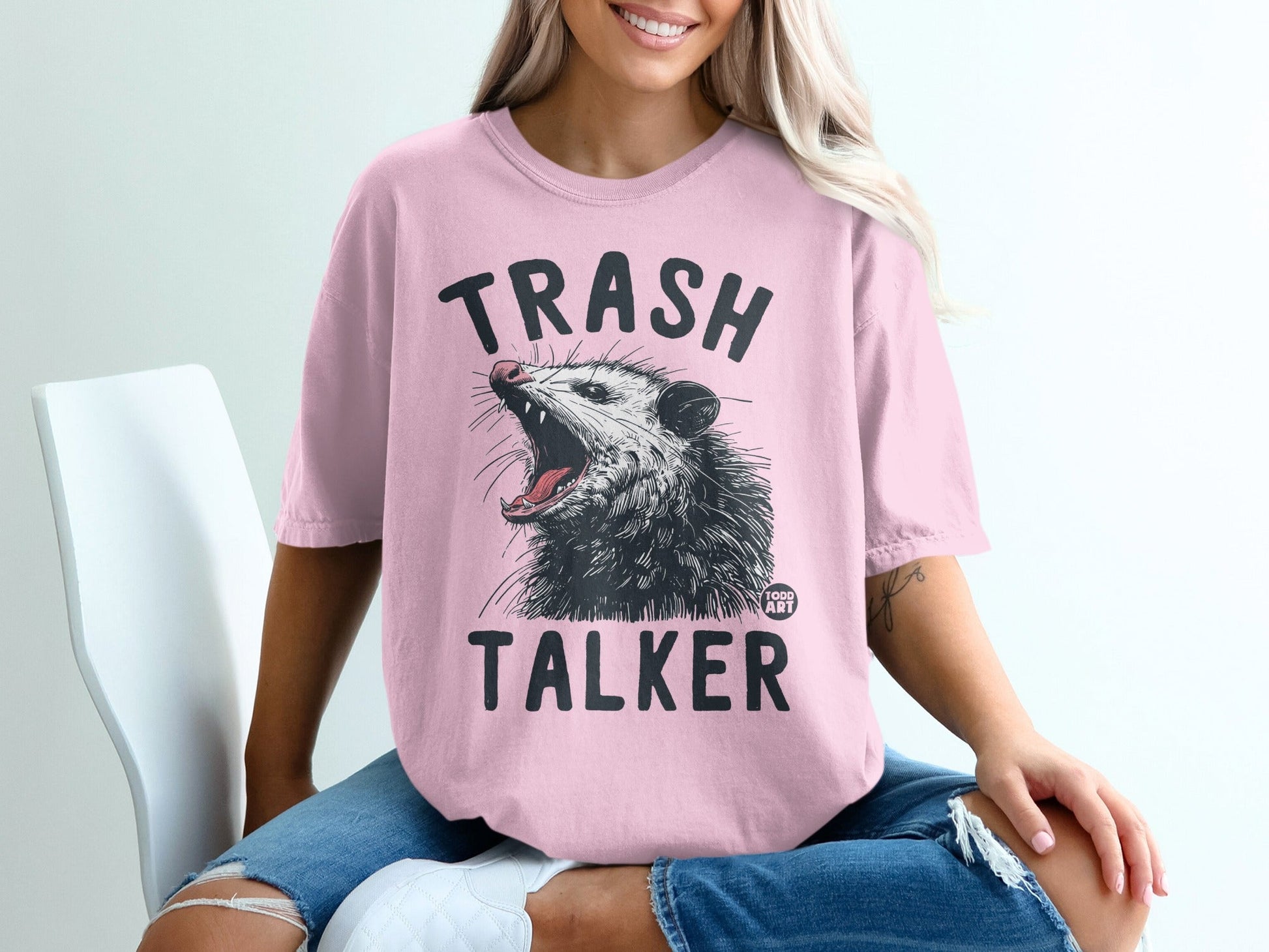Pink t-shirt with "TRASH TALKER" text and a detailed illustration of a snarling opossum.