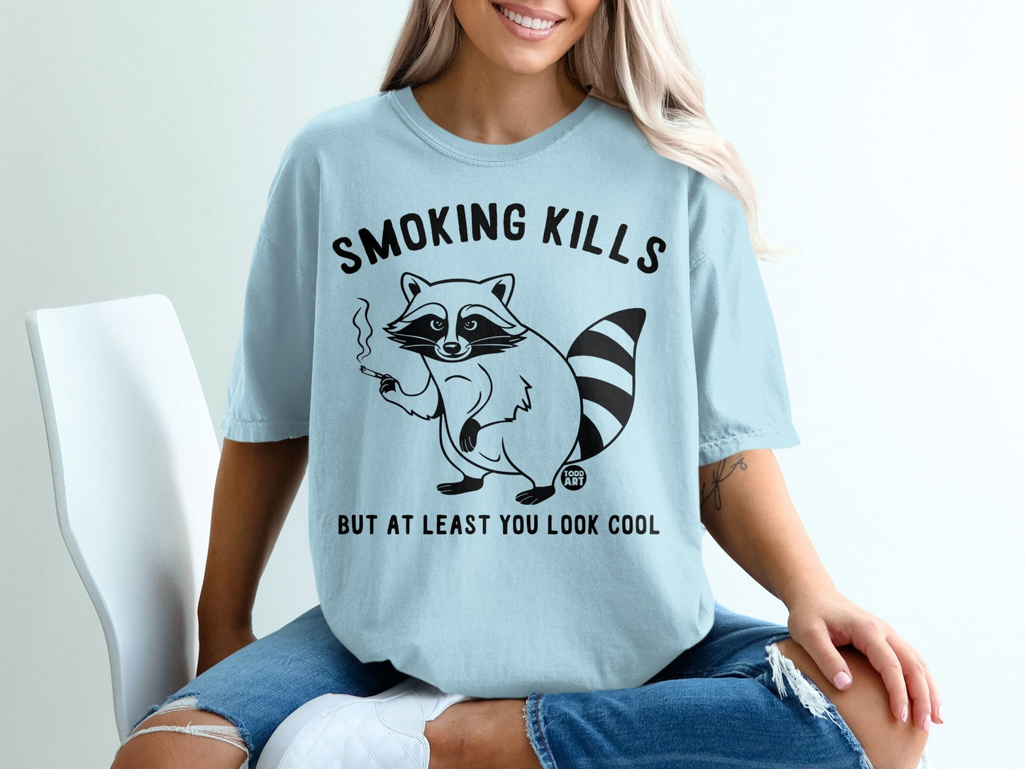 Light blue t-shirt with raccoon smoking, "Smoking kills but at least you look cool" text.