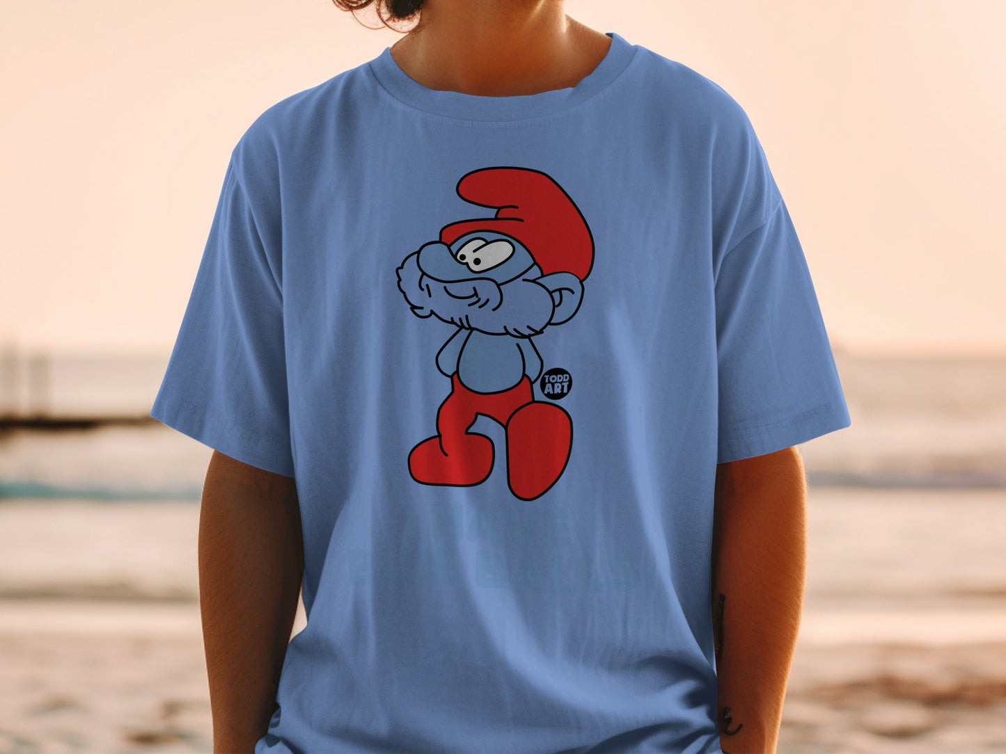 Blue t-shirt with a cartoon illustration of a Smurf in red hat and pants.