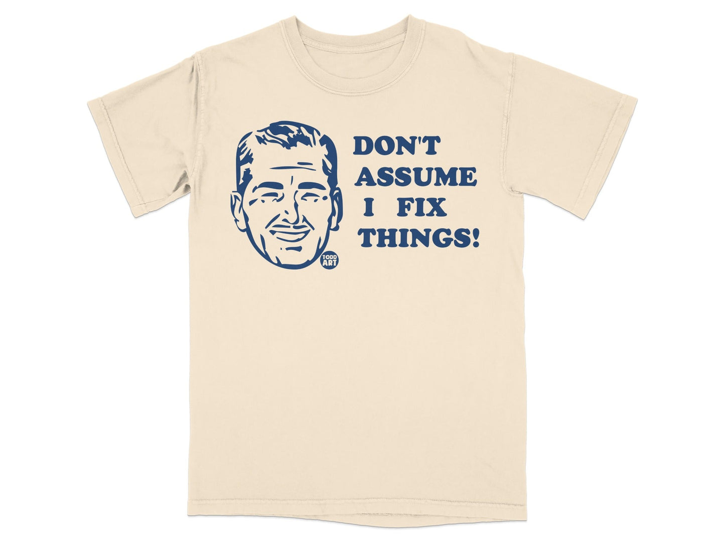 Cream t-shirt with a blue graphic of a man's face and text "DON'T ASSUME I FIX THINGS!".