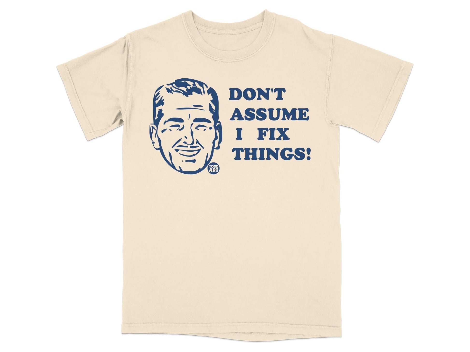 Cream t-shirt with a blue graphic of a man's face and text "DON'T ASSUME I FIX THINGS!".