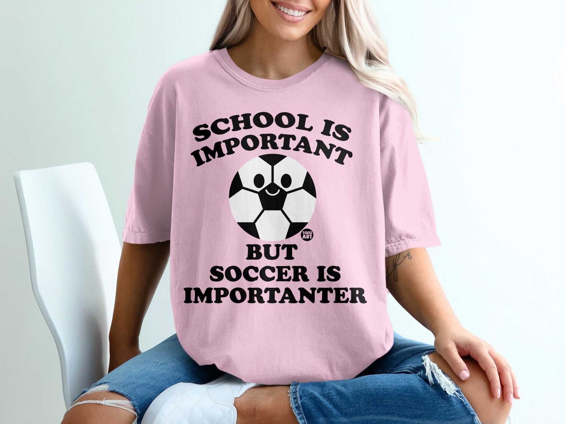 Pink t-shirt with "SCHOOL IS IMPORTANT BUT SOCCER IS IMPORTANTER" and a smiling soccer ball.