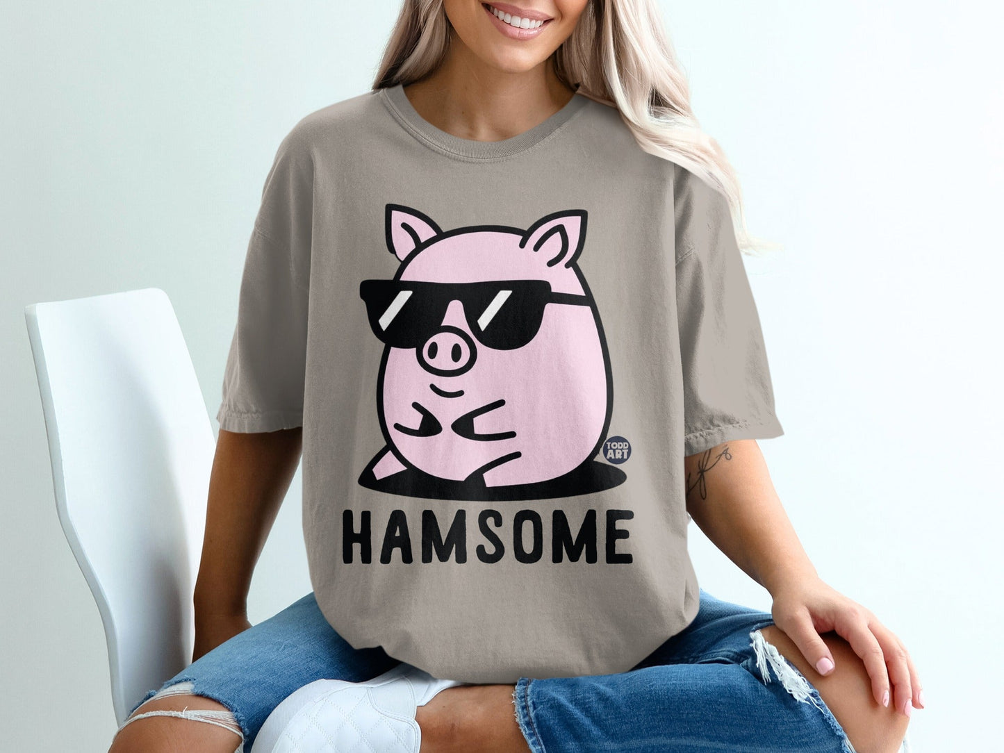 Pink pig wearing sunglasses, "HAMSOME" text on a beige t-shirt.