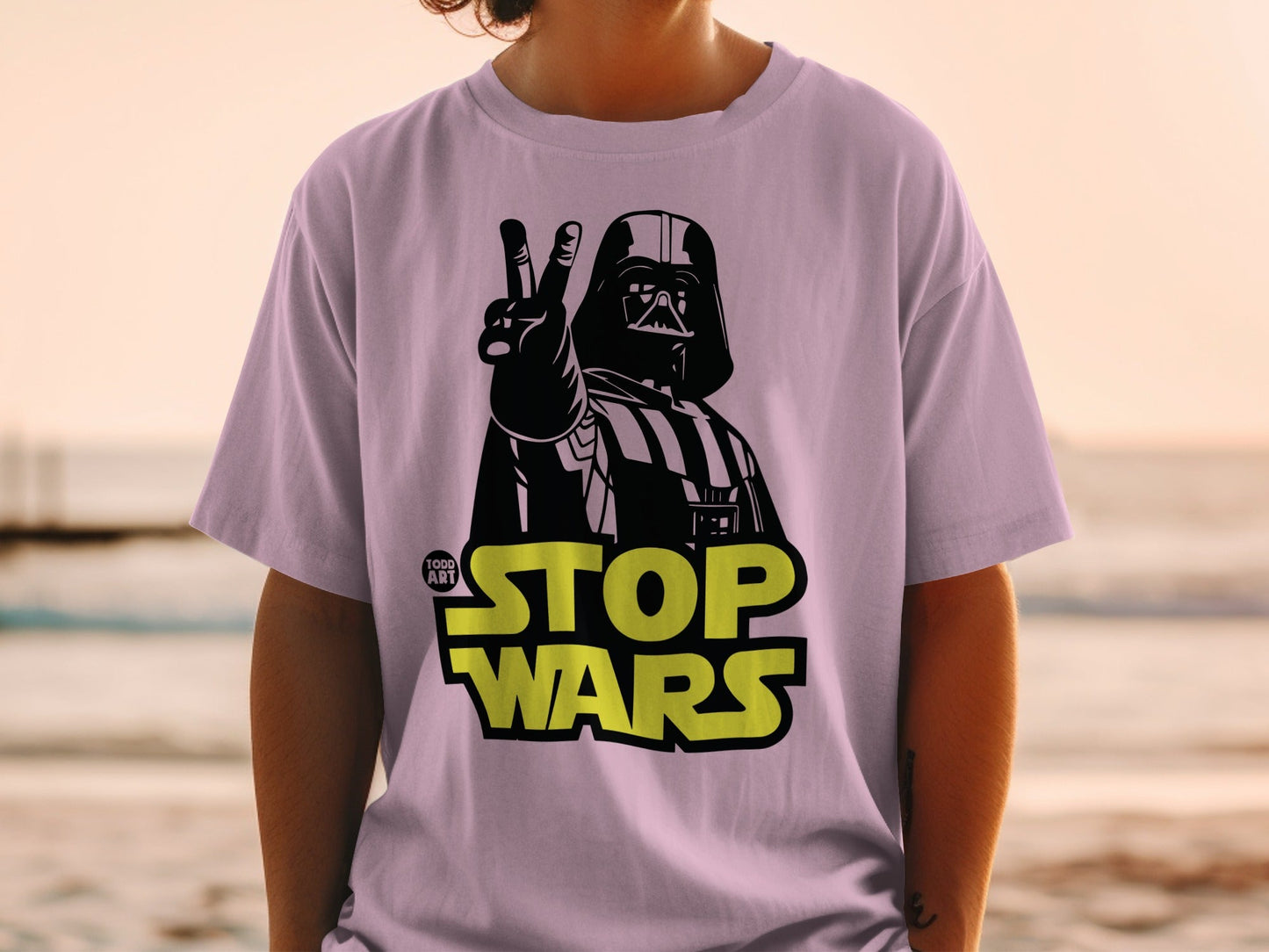 Darth Vader giving peace sign on purple t-shirt with yellow "STOP WARS" text.
