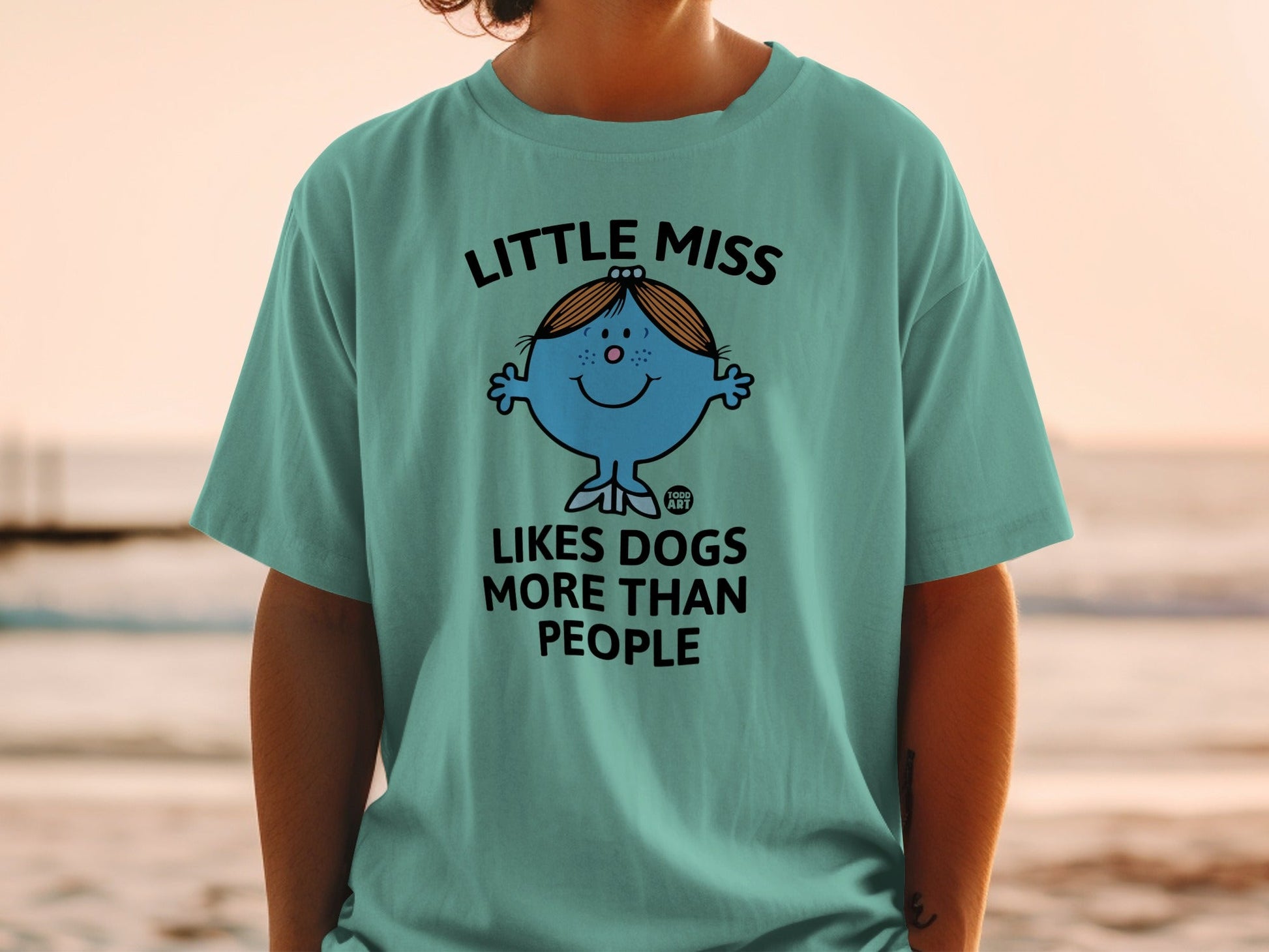 Blue cartoon character "Little Miss" t-shirt with text "LITTLE MISS LIKES DOGS MORE THAN PEOPLE".