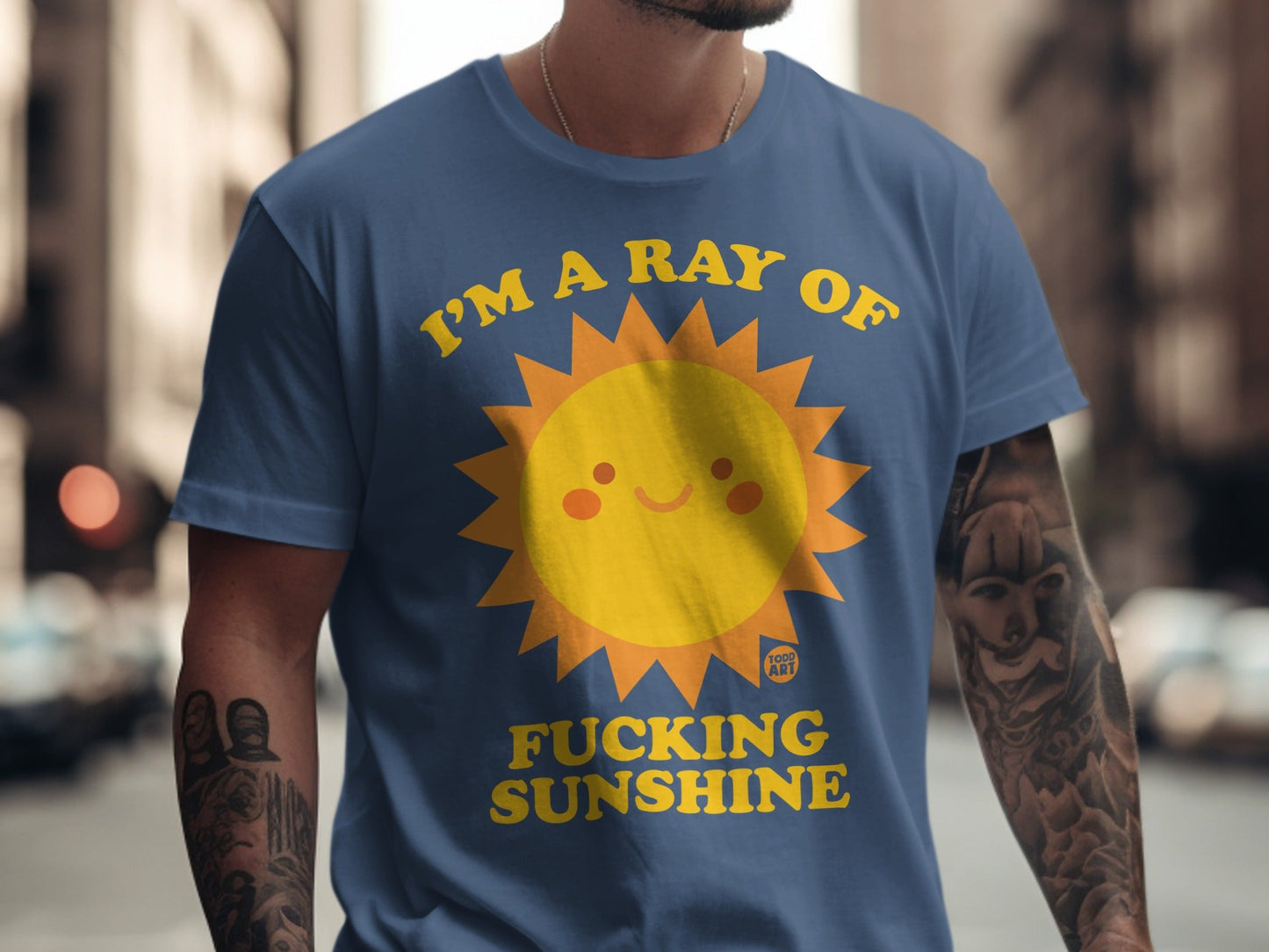 Blue t-shirt with a smiling sun graphic and the text "I'M A RAY OF FUCKING SUNSHINE".