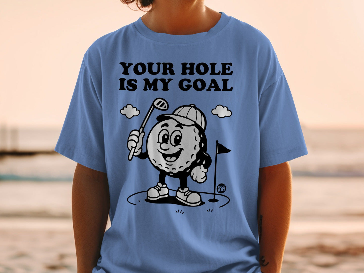 Blue t-shirt with cartoon golf ball character and "YOUR HOLE IS MY GOAL" text.