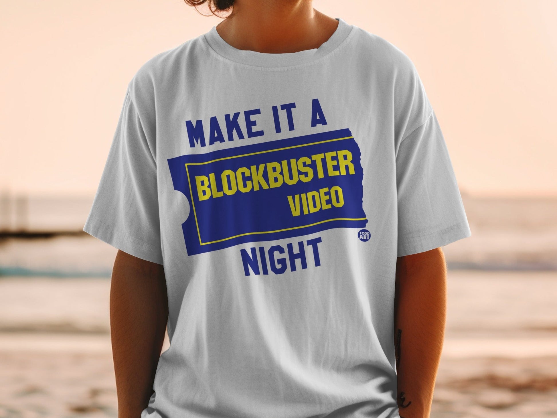 White t-shirt with "Make it a Blockbuster Night" in yellow and blue.