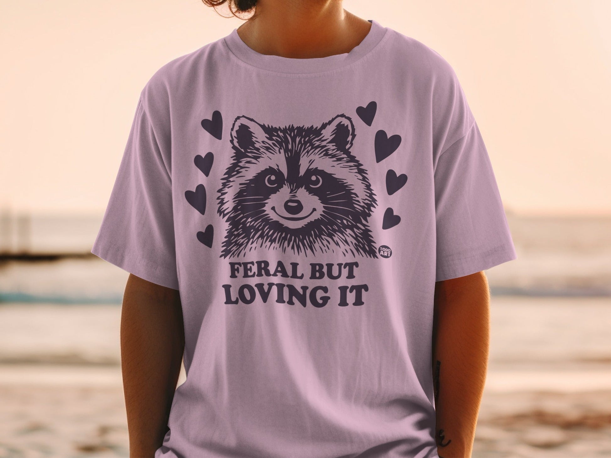 Purple t-shirt with raccoon graphic and "Feral But Loving It" text.