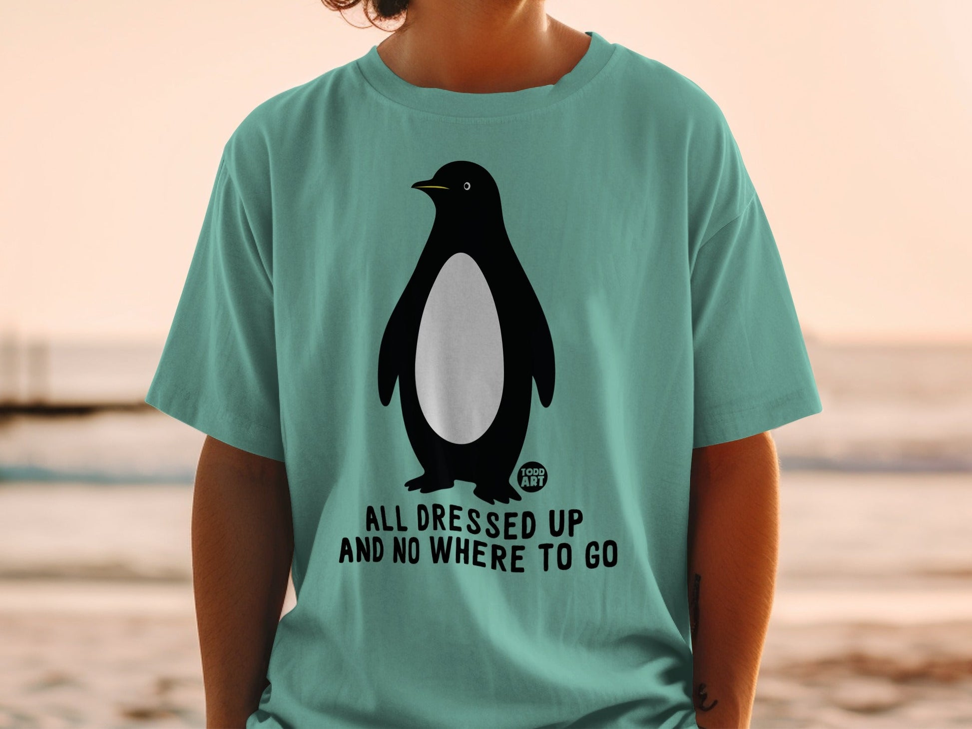 Teal t-shirt with a penguin graphic and text: "All dressed up and no where to go."