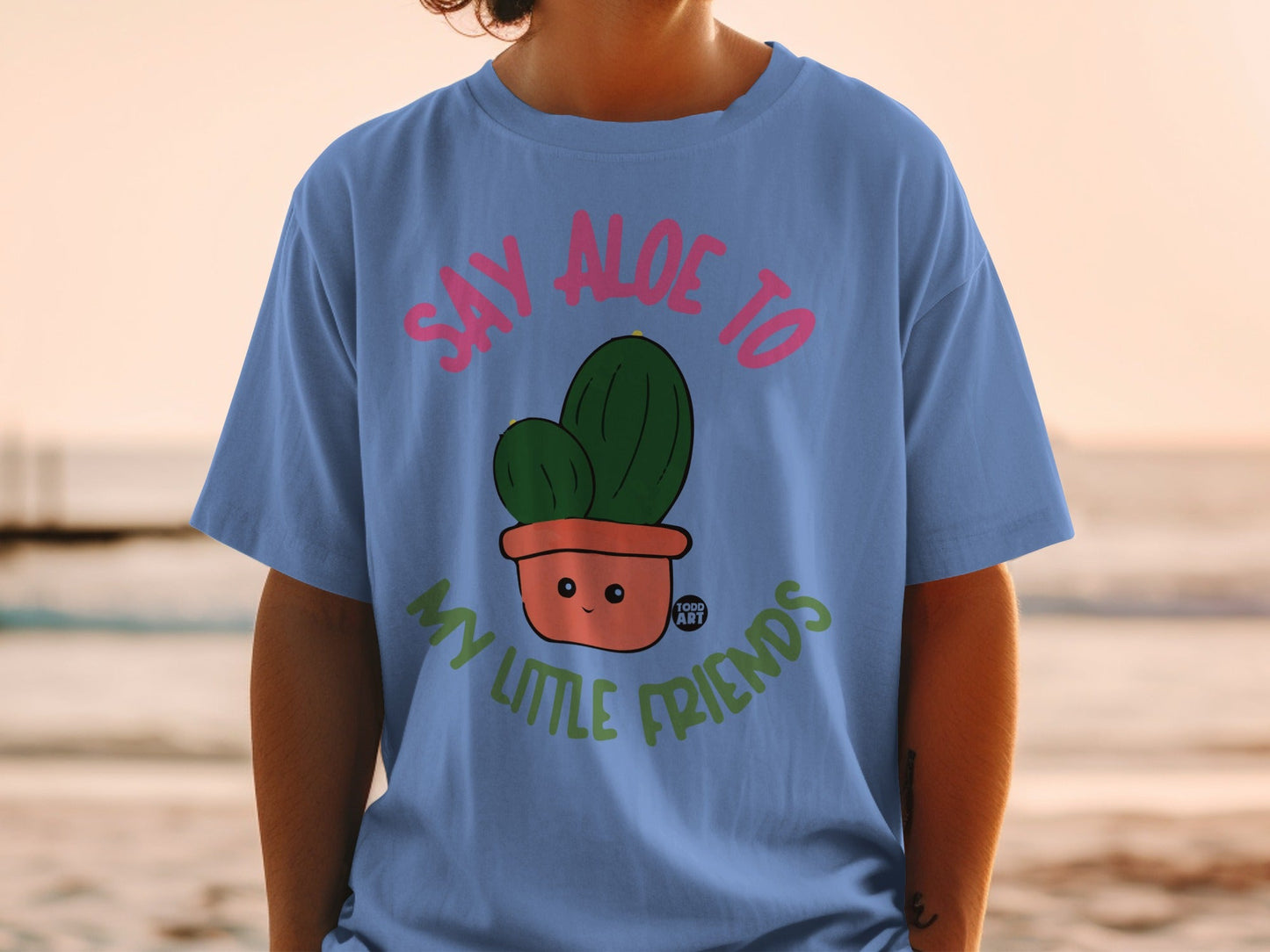 Blue t-shirt with cartoon cactus saying "Say aloe to my little friends".