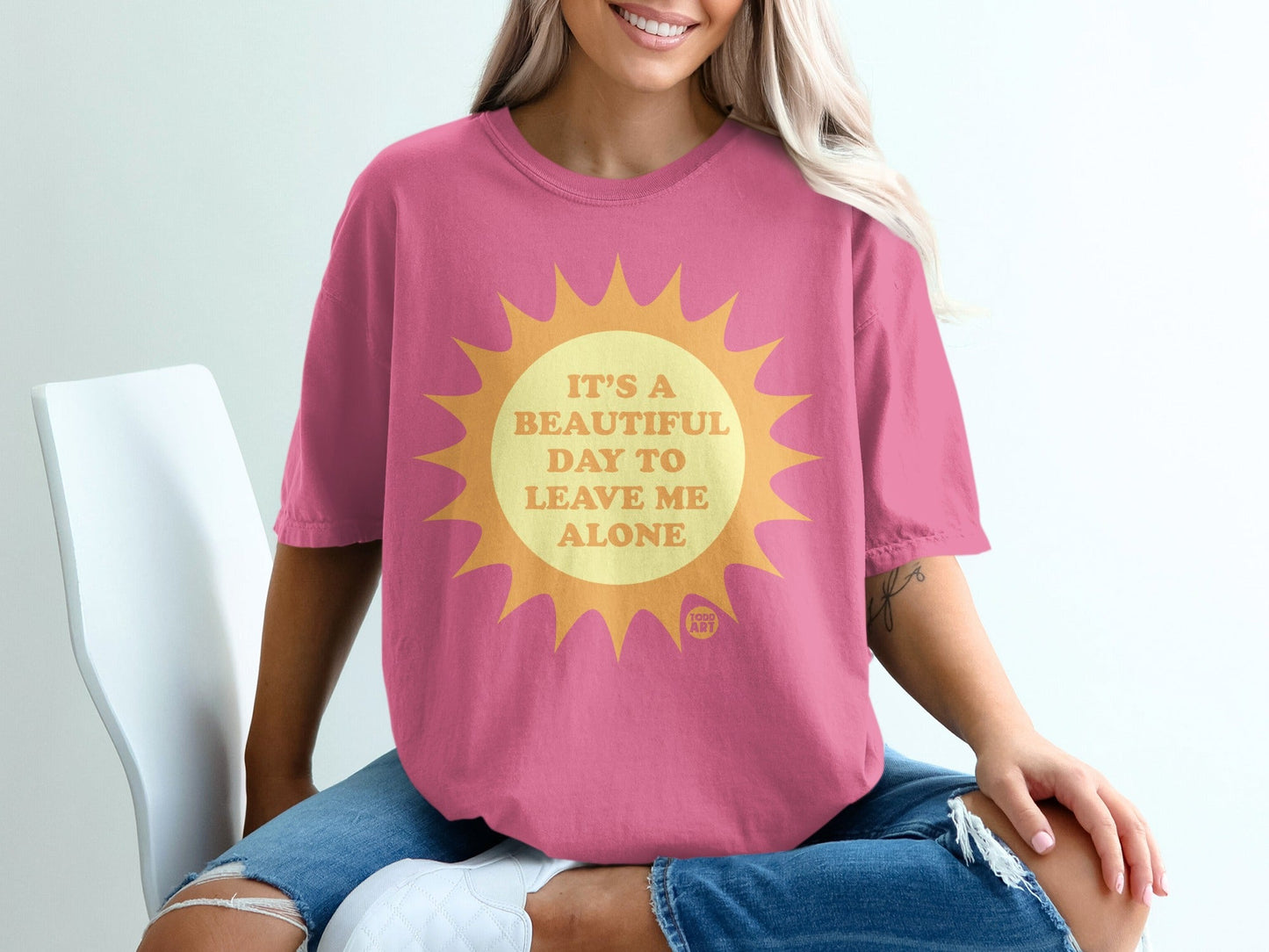 Pink t-shirt with a sun graphic and text "It's a beautiful day to leave me alone."