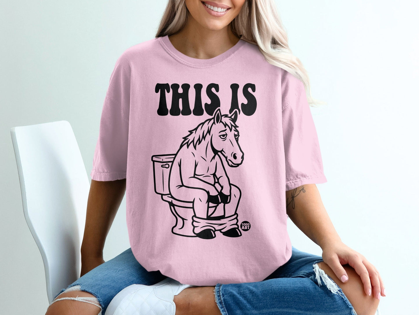 T-shirt with a cartoon horse sitting on a toilet, text reads "THIS IS".