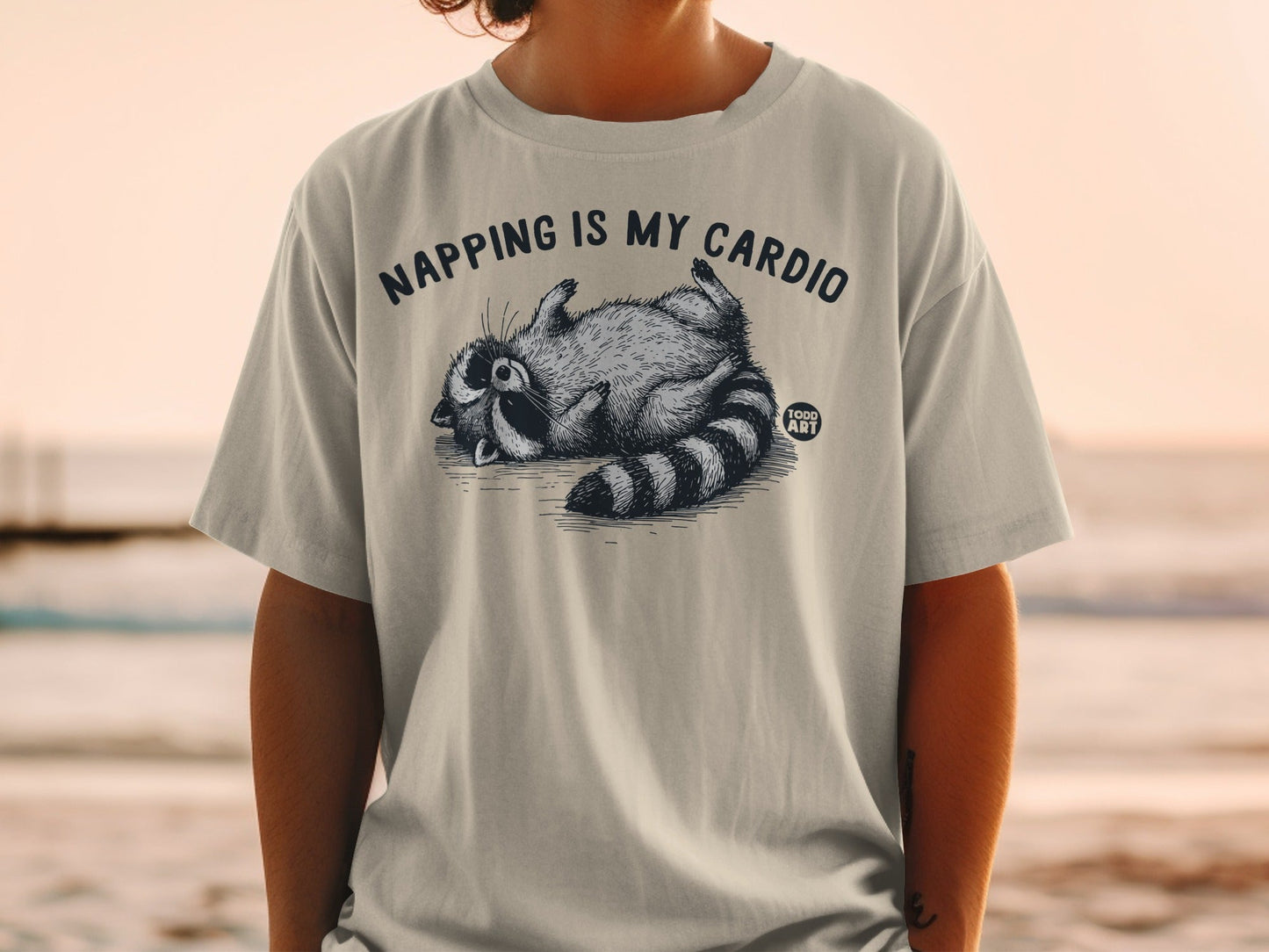 T-shirt with raccoon sleeping and text "Napping is my cardio".