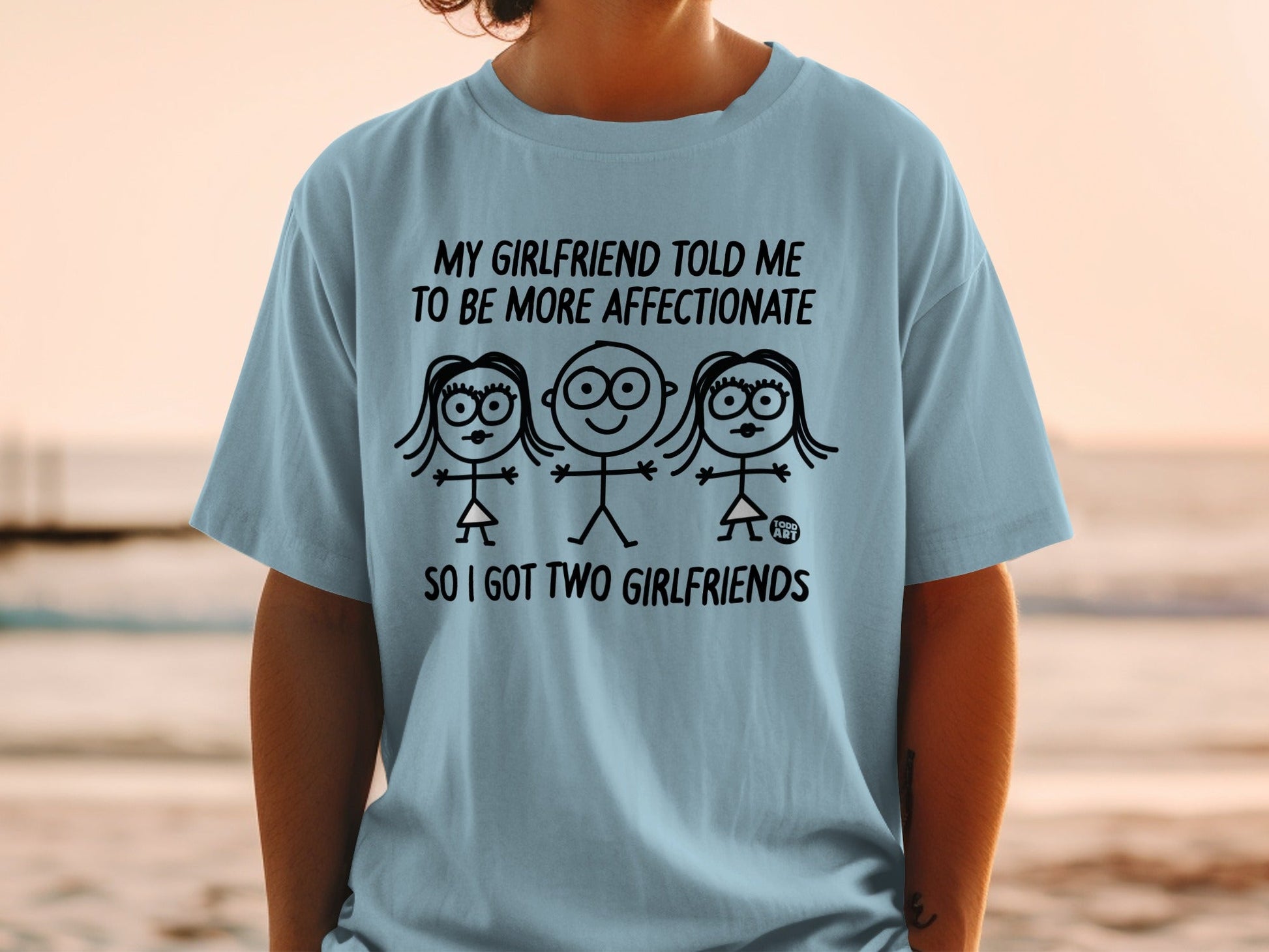 Light blue t-shirt with three stick figures and text about having two girlfriends.