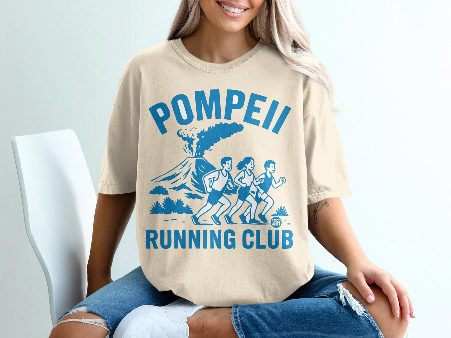 Pompeii Running Club graphic on a light beige t-shirt with volcano and runners.
