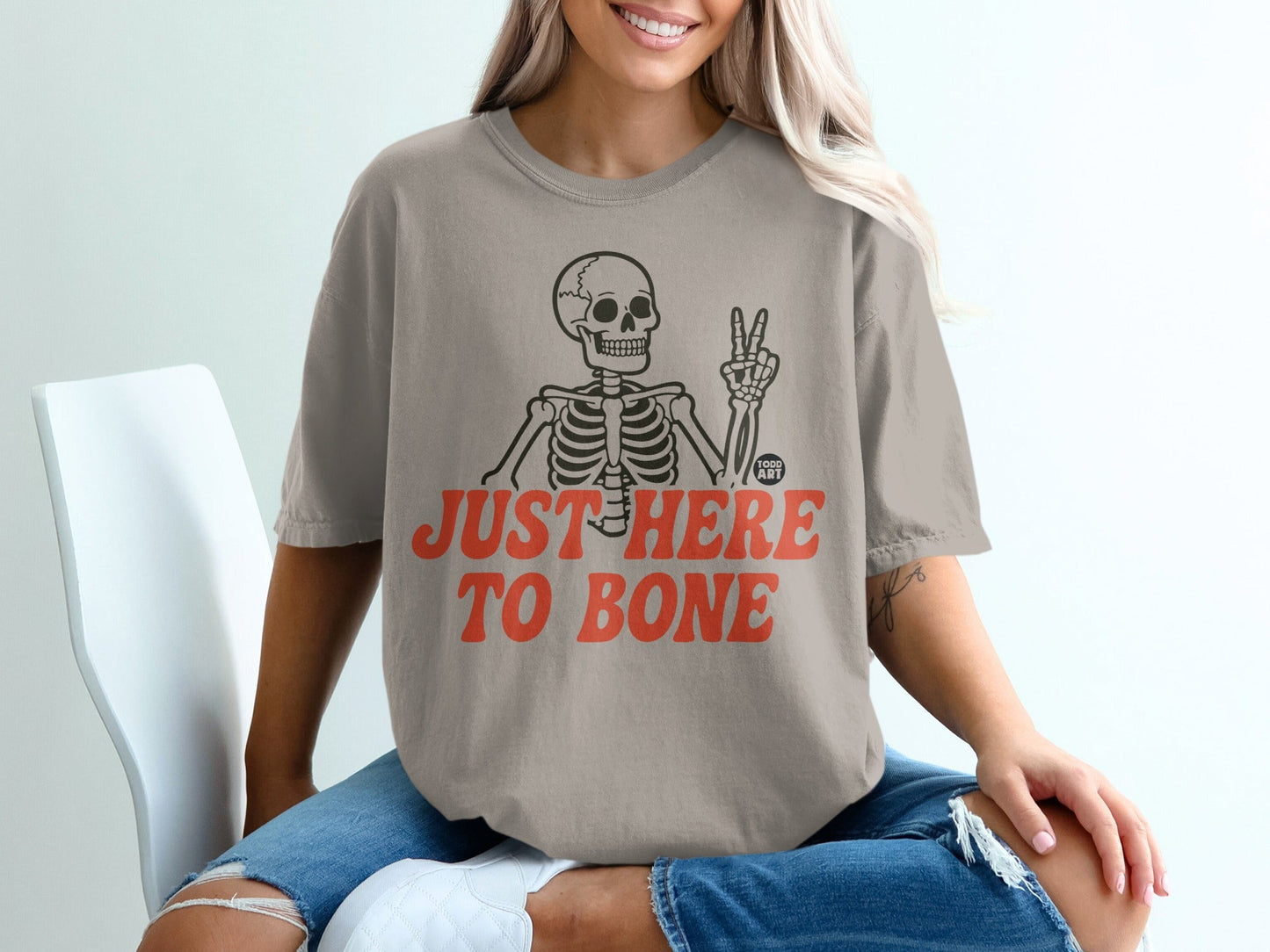 Skeleton in t-shirt with "JUST HERE TO BONE" text and peace sign.