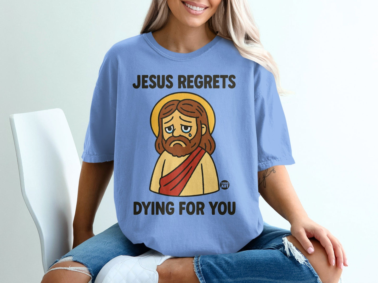 Light blue t-shirt with graphic of sad Jesus saying "Jesus regrets dying for you."