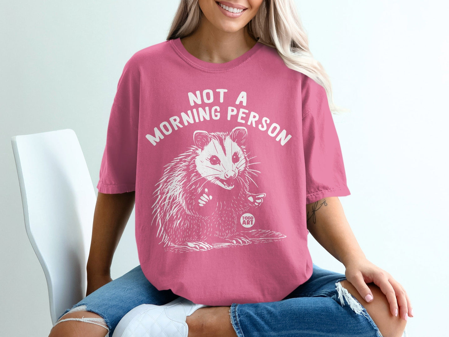 Pink t-shirt with white text "NOT A MORNING PERSON" and opossum graphic.