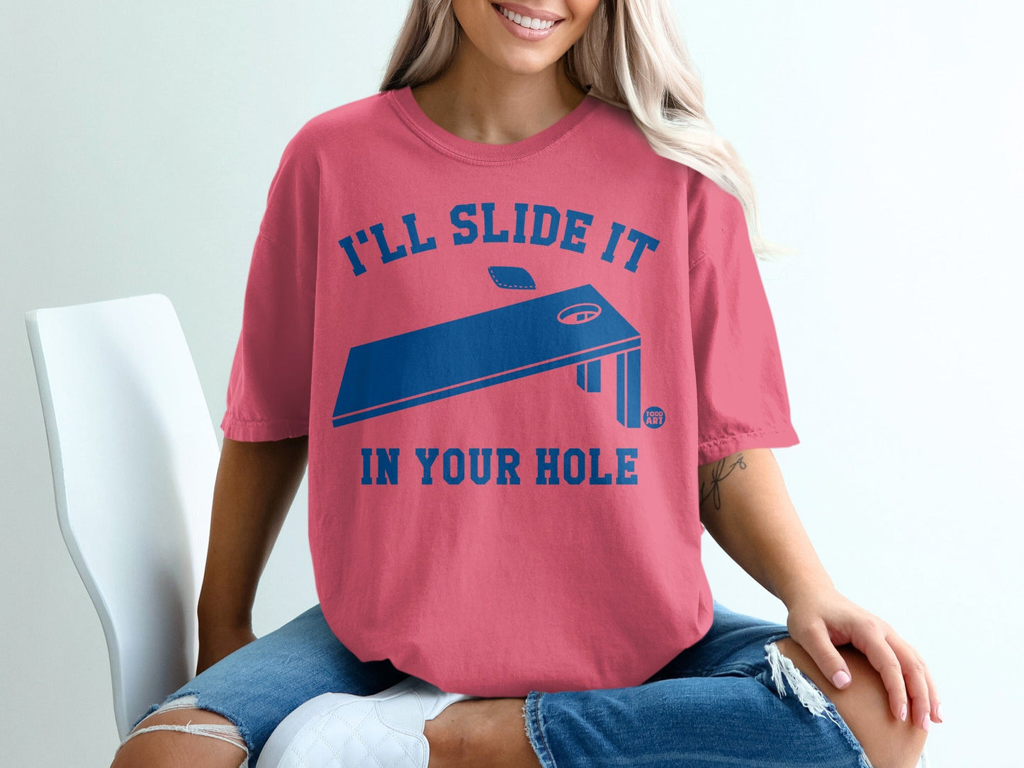 Coral t-shirt with blue cornhole graphic and text "I'll slide it in your hole."