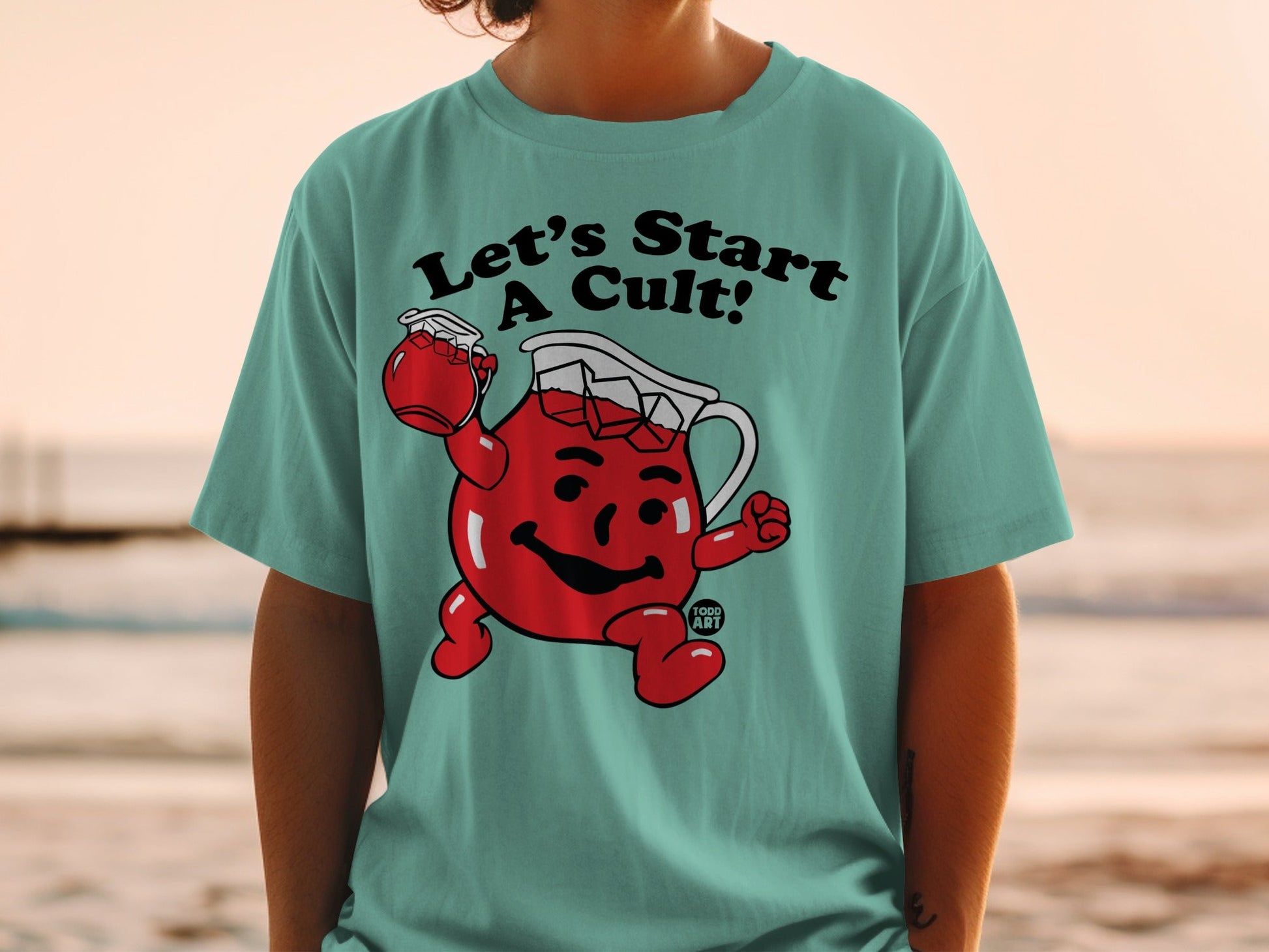 Teal t-shirt with cartoon Kool-Aid pitcher and text "Let's Start A Cult!".