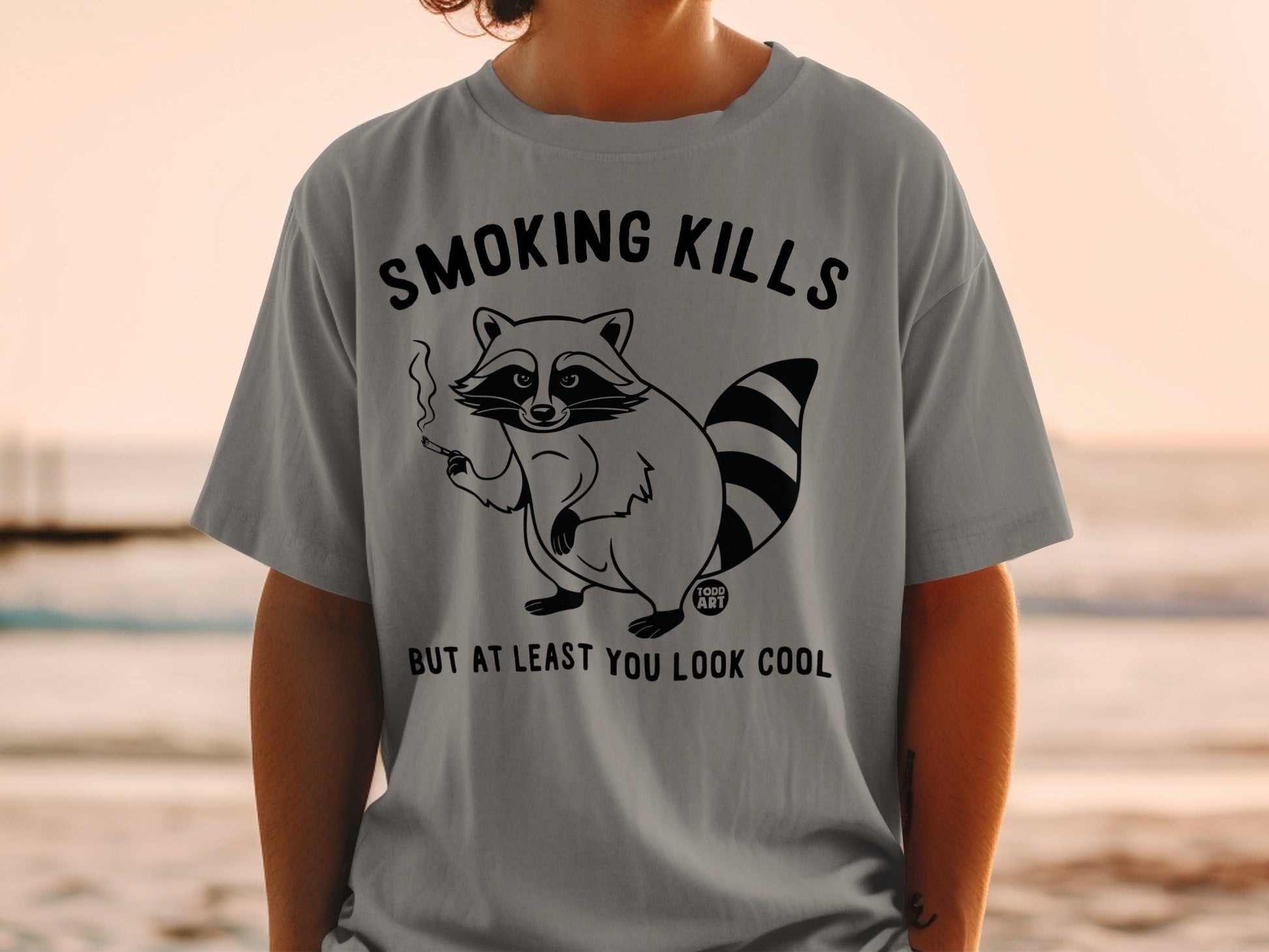 Gray t-shirt with "Smoking Kills But At Least You Look Cool" graphic featuring a raccoon smoking.