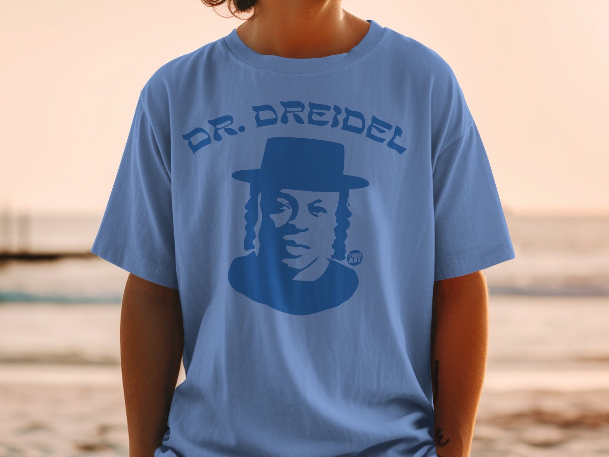 Blue t-shirt with a silhouetted man wearing a hat and the text "DR. DREIDEL"