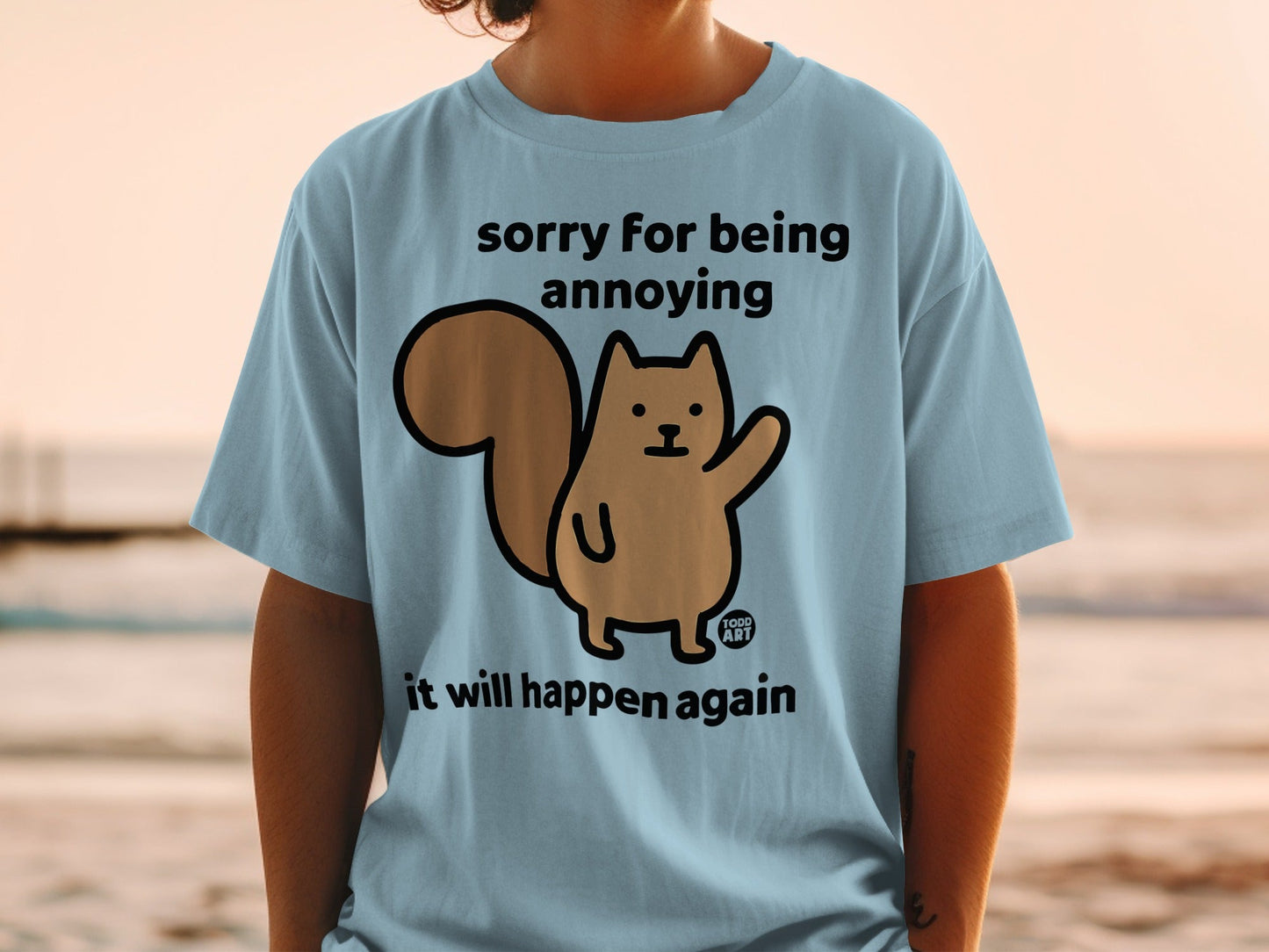 Light blue t-shirt with cartoon squirrel saying "sorry for being annoying it will happen again".
