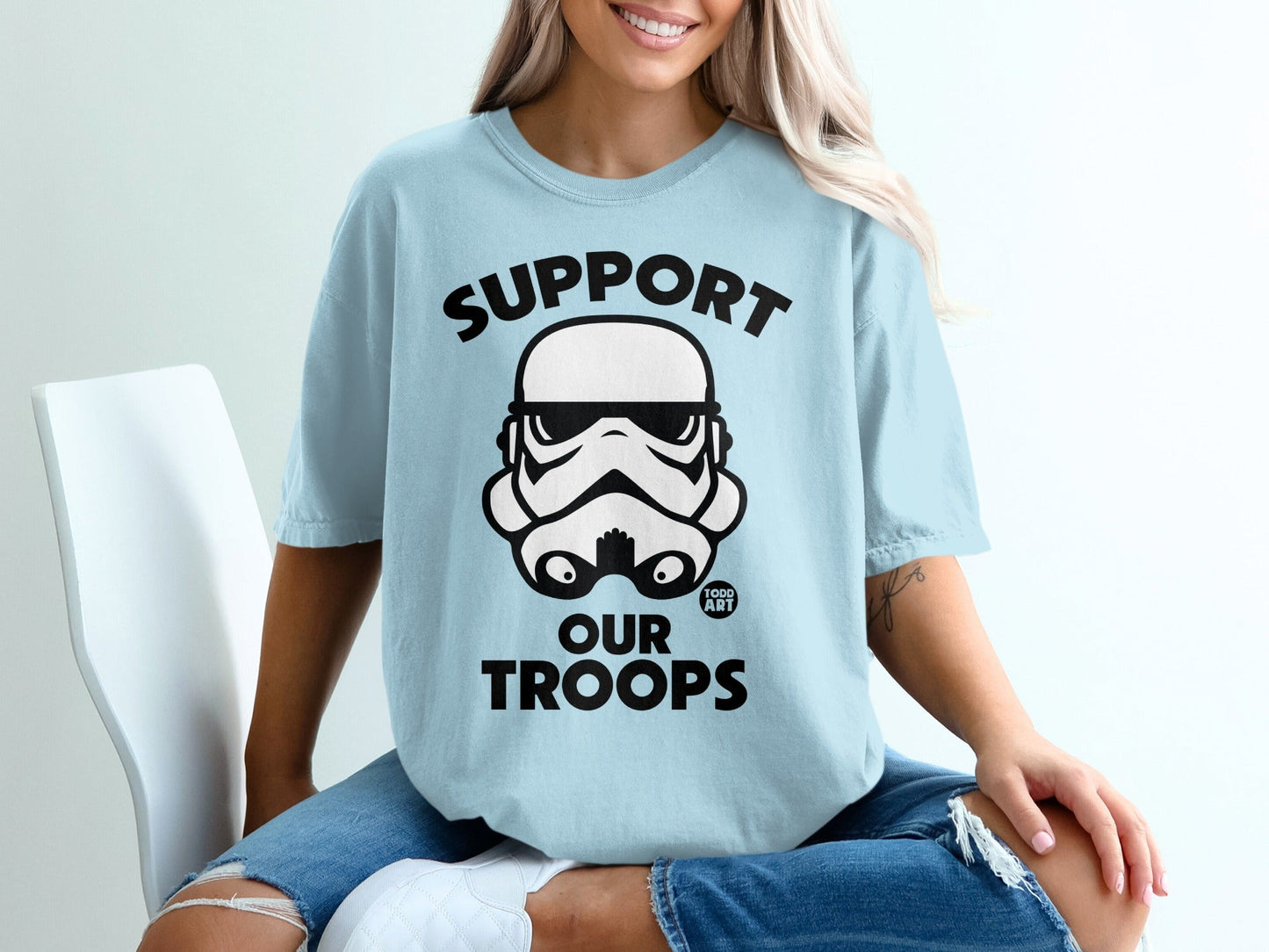 Light blue t-shirt with black Stormtrooper helmet and "SUPPORT OUR TROOPS" text.